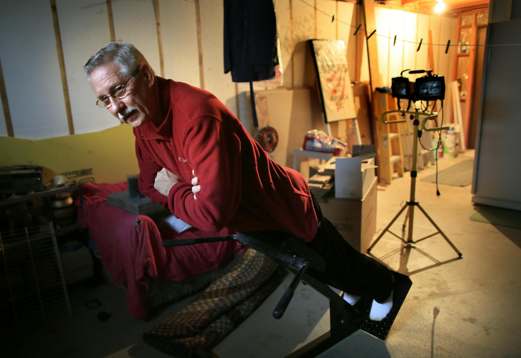 Ken Bueckers, a former pipe fitter whose back has blown out several times, works on his morning stretching routine before he begins his day. He cannot keep working. His leg is numb and he has drop foot. A divide is growing in American society between the prospects in delayed retirement for white collar and blue collar workers. Workers steeped in the skills and language of the information economy can put his hard-won experience to work well past the traditional retirement age. The same will not b