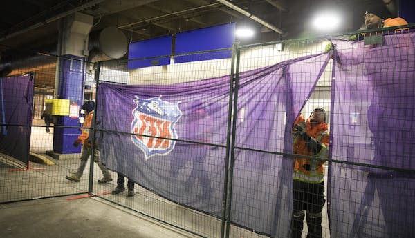 Skippy Narayan, from right, and Alexander Rioux from MODU-LOC USA build a barrier to direct passengers on Sunday without Super Bowl tickets to the bus