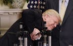 US President Donald Trump uses a machine to attempt to crush a newly designed, Made in America pharmaceutical glass bottle during a Made in America We