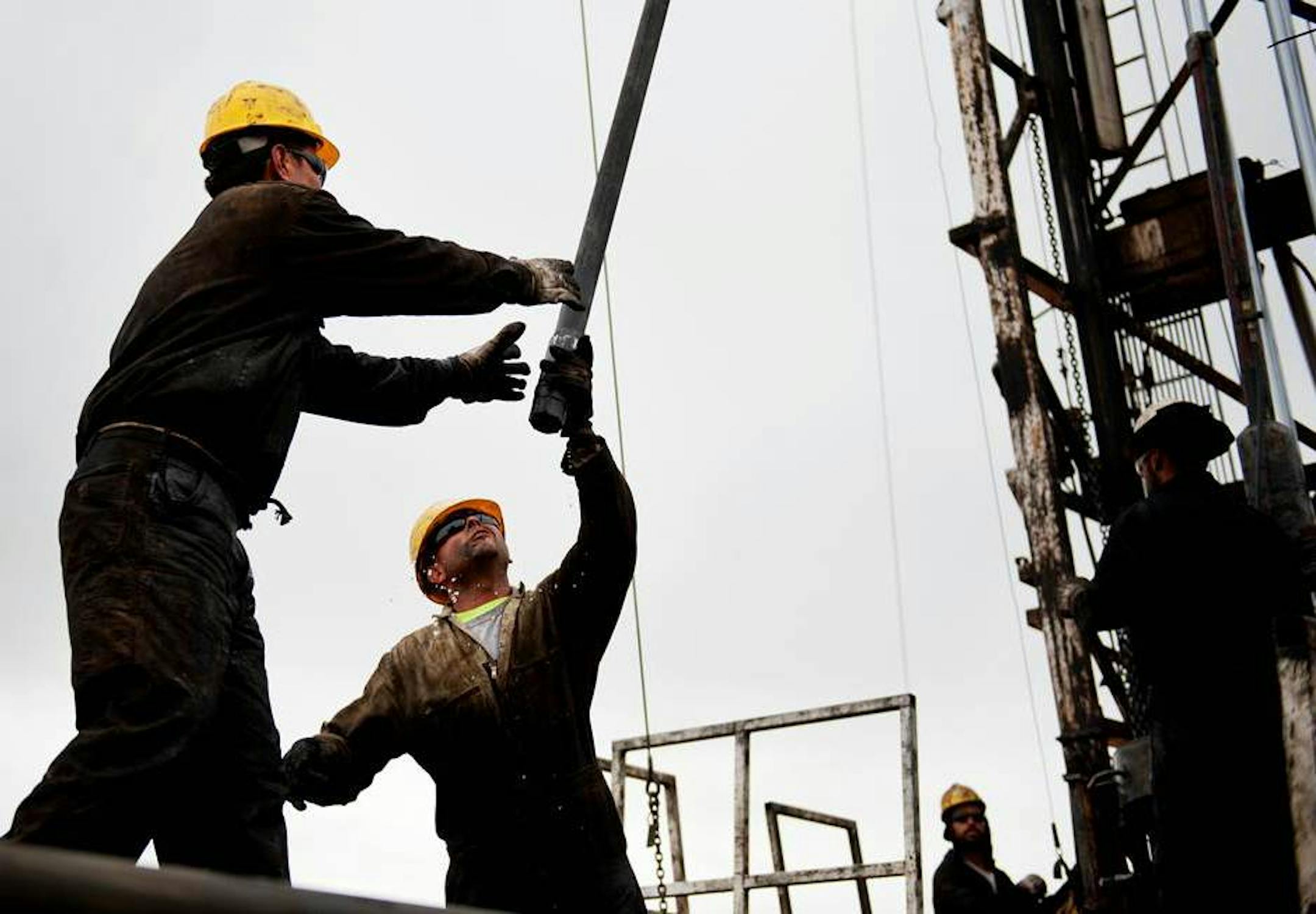 This Oct. 9, 2013 photo shows Precision Well Service rig hands Ricardo Castillon, left, and Gerardo Aguilar as they lay tubing pipe from a workover rig. Precision Well Service Vice President Bryan Lass says increased oil production in the Powder River Basin has kept his crews working at 100 percent for the past six months. (AP Photo/Gillette News Record, Daniel Brenner)