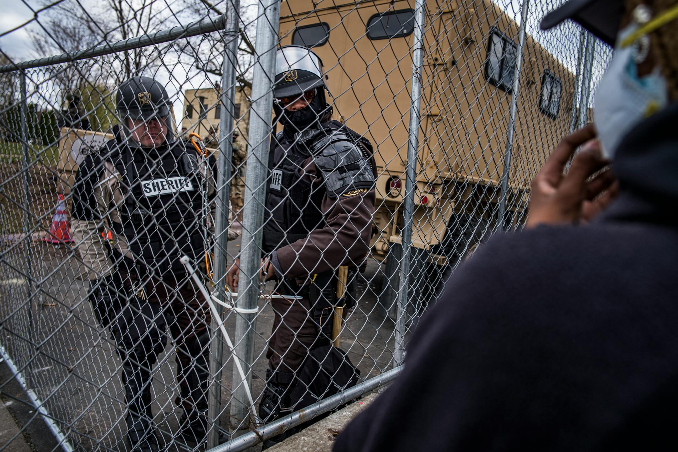 Law enforcement officers looked through a fence as people protest near the Brooklyn Center Police Department in response to the fatal police shooting of Daunte Wright, Thursday, April 15, 2021 in Brooklyn Center, Minn.