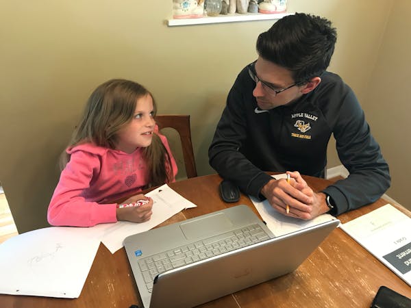 Lydia Goessling, a second-grader at Hale Elementary, does school work with her dad, Ben Goessling, the Star Tribune's Vikings beat reporter.