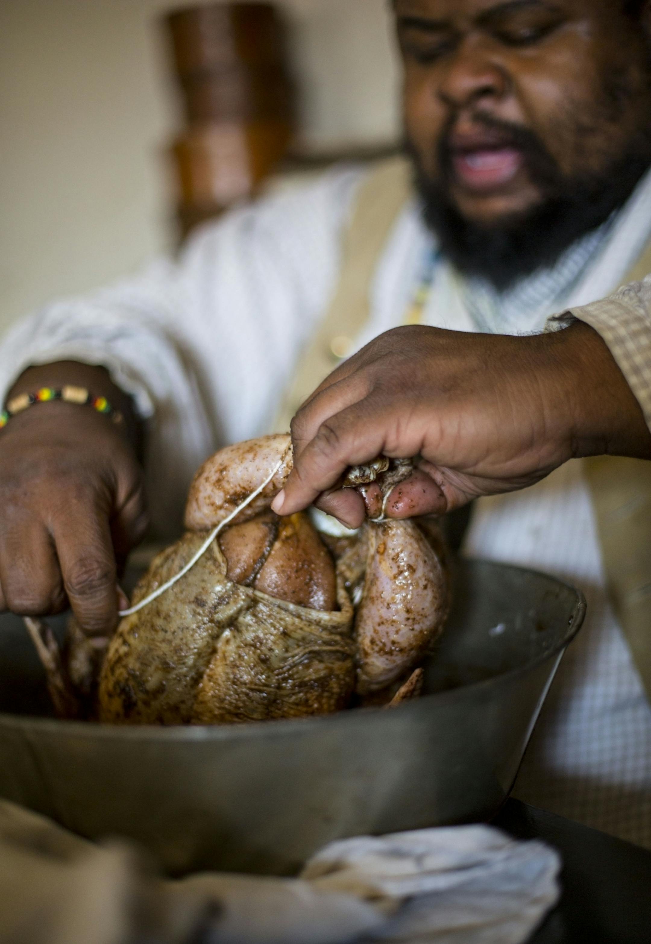 Michael Twitty binds the chicken together with twine before covering it in cabbage leaves to cook.