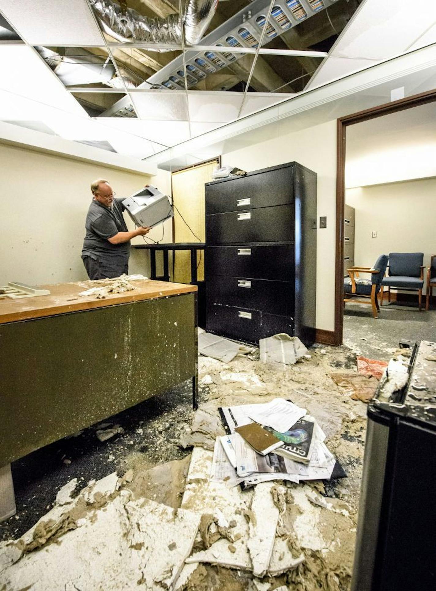 Fiscal Analyst Doug Berg carried a wet printer from his flooded office on the third floor of the State Office Building at the State Capitol. The ceiling tiles had fallen down.