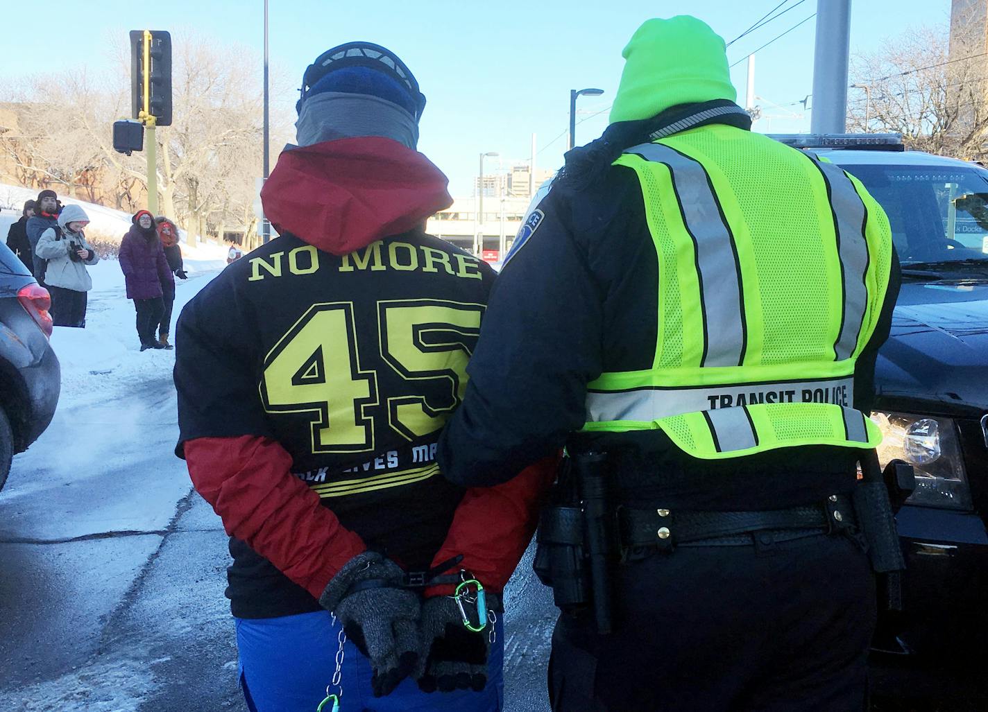 Transit police escort a protester away after people formed a human blockade Sunday afternoon across light rail tracks at the West Bank station just east of U.S. Bank Stadium, where Super Bowl LII was scheduled to kick off early in the evening.