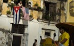 FILE - In this July 20, 2015, file photo, Javier Yanez looks out from his balcony where he hung a U.S., and a Cuban national flag, to celebrate the re