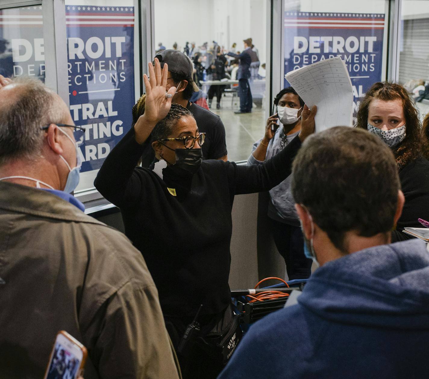 A Detroit Department of Elections worker pushes the crowd back as absentee ballots are counted in the next room in Detroit, Nov. 4, 2020.