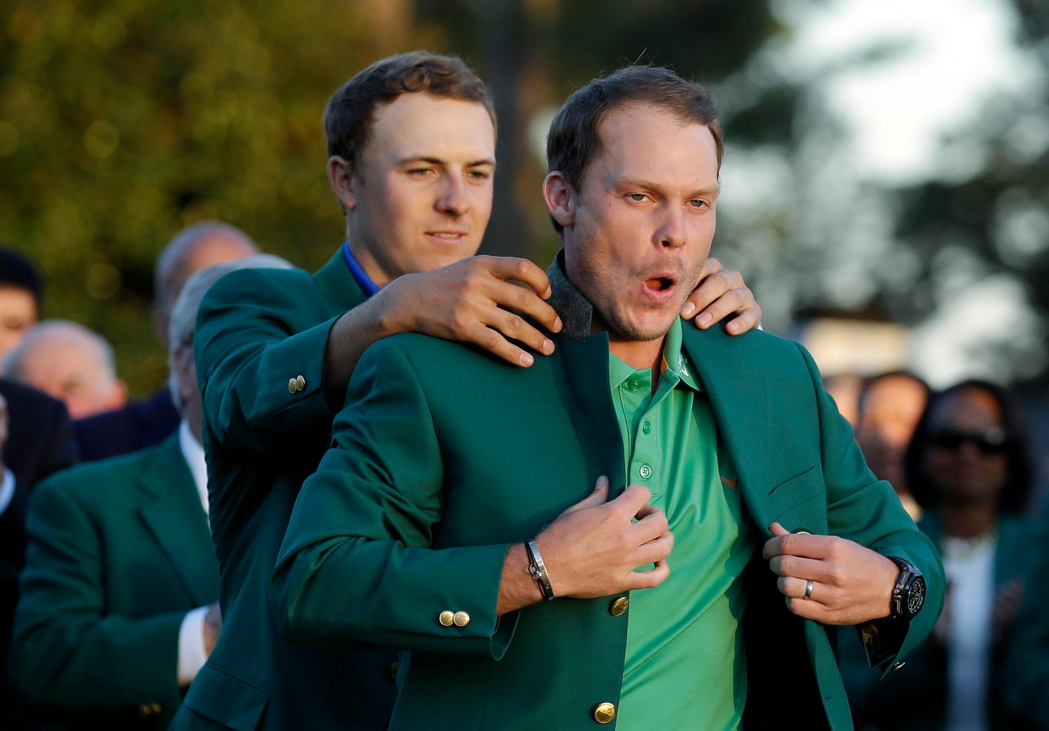 Defending champion Jordan Spieth, left, helps 2016 Masters champion Danny Willett put on his green jacket following Sunday's final round.