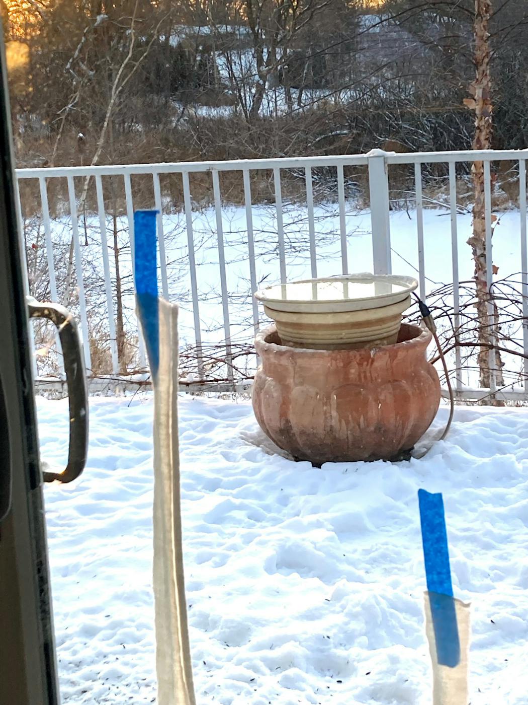 The bird bath is atop that pot against the deck railing. The blue mark is masking tape holding cotton strips to warn birds of the glass. Six patio doors, two strips per window. They blow in a breeze, and work like a charm. Inexpensive, too.