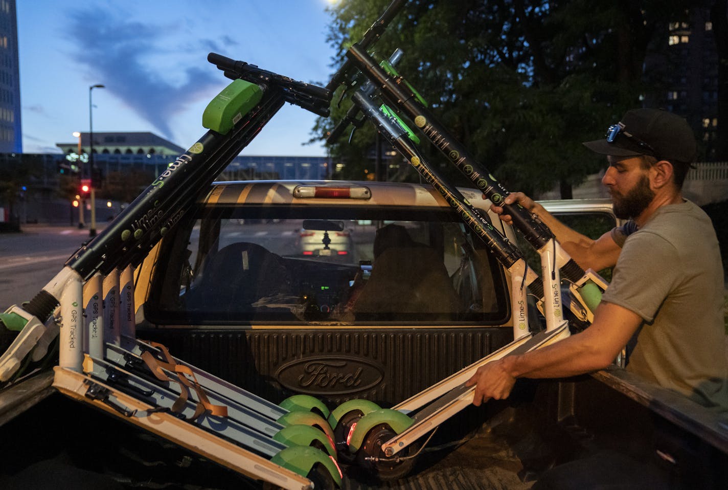 Emerson loaded scooters onto his pickup truck while his wife, Sarah, waited in the cab. They estimate making between $4 and $8 for every scooter they take home, charge and drop off.