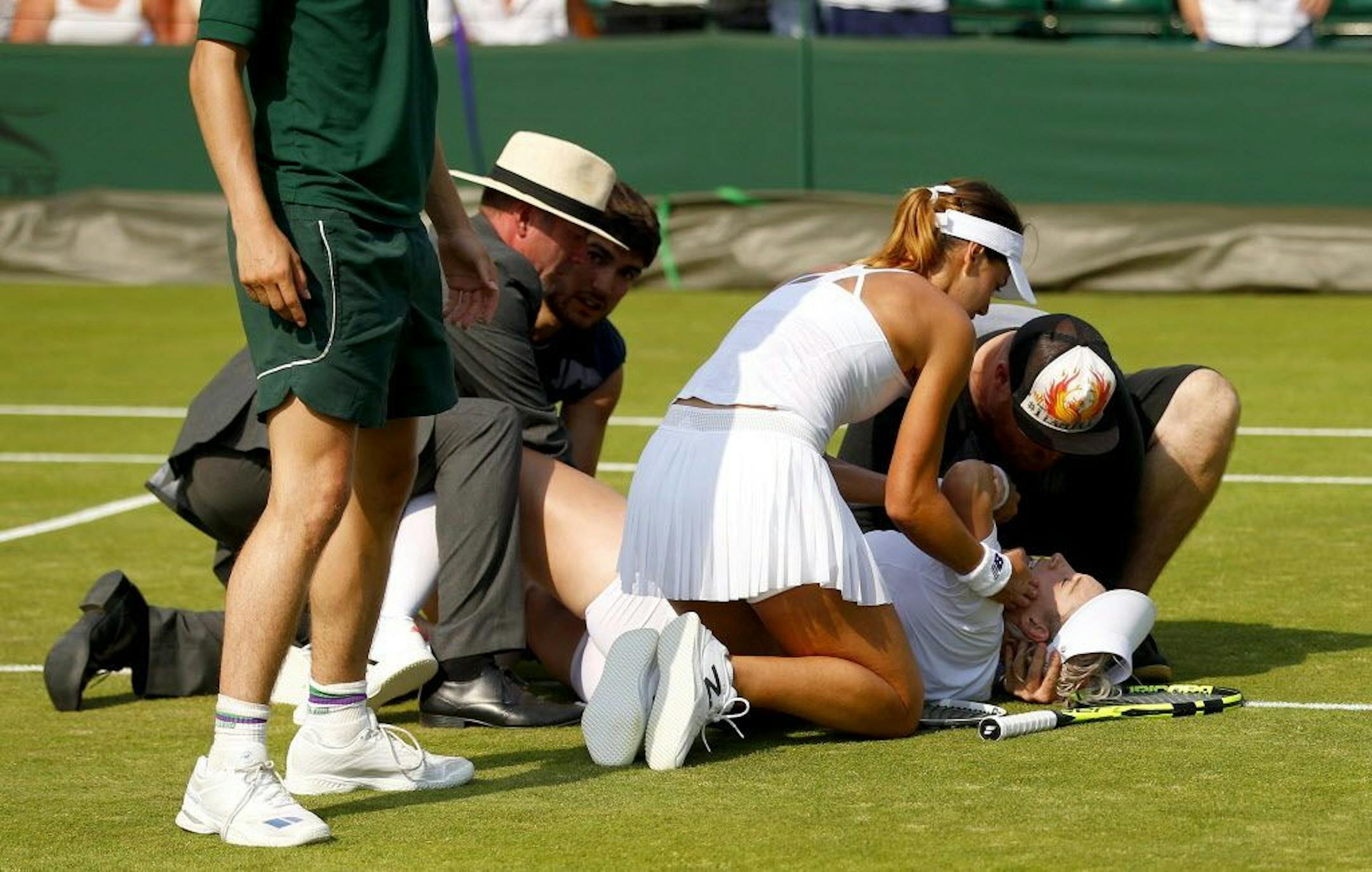Betthanie Mattek Sands of USA lies in pain on the court as Sorana Cirstea helps her Wimbledon 2017, Day 4, All England Lawn Tennis Club, London UK, 06 July 2017
