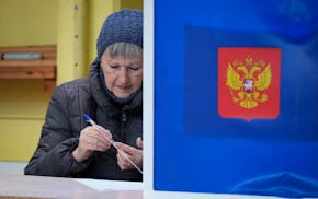 A woman checks a pen prior to filling in her ballot at a pooling station during a presidential election in St. Petersburg, Russia, Friday, March 15, 2