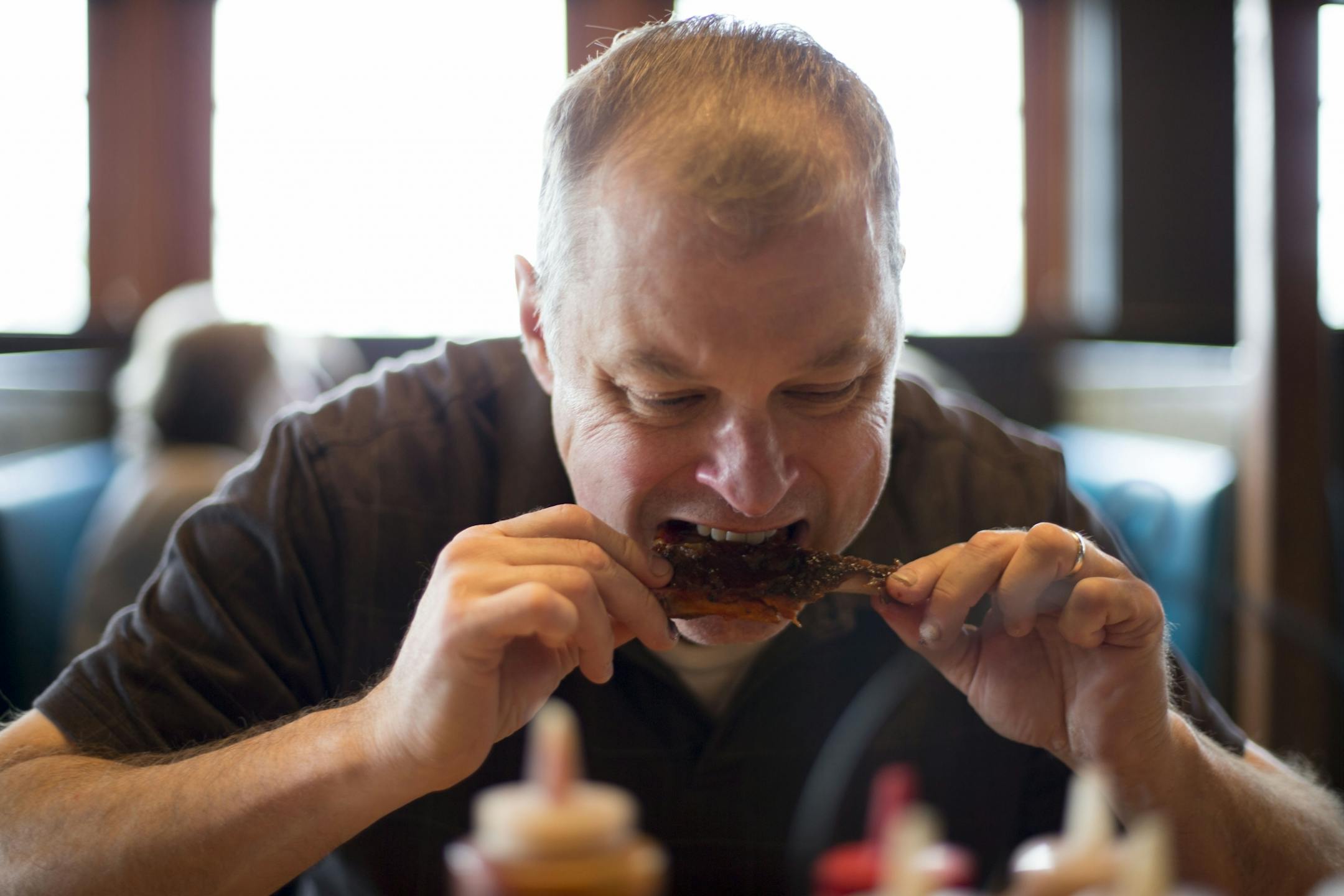 Steve Halicki bites into a St. Louis style BBQ rib at the bar at Famous Dave's during lunch on Thursday.