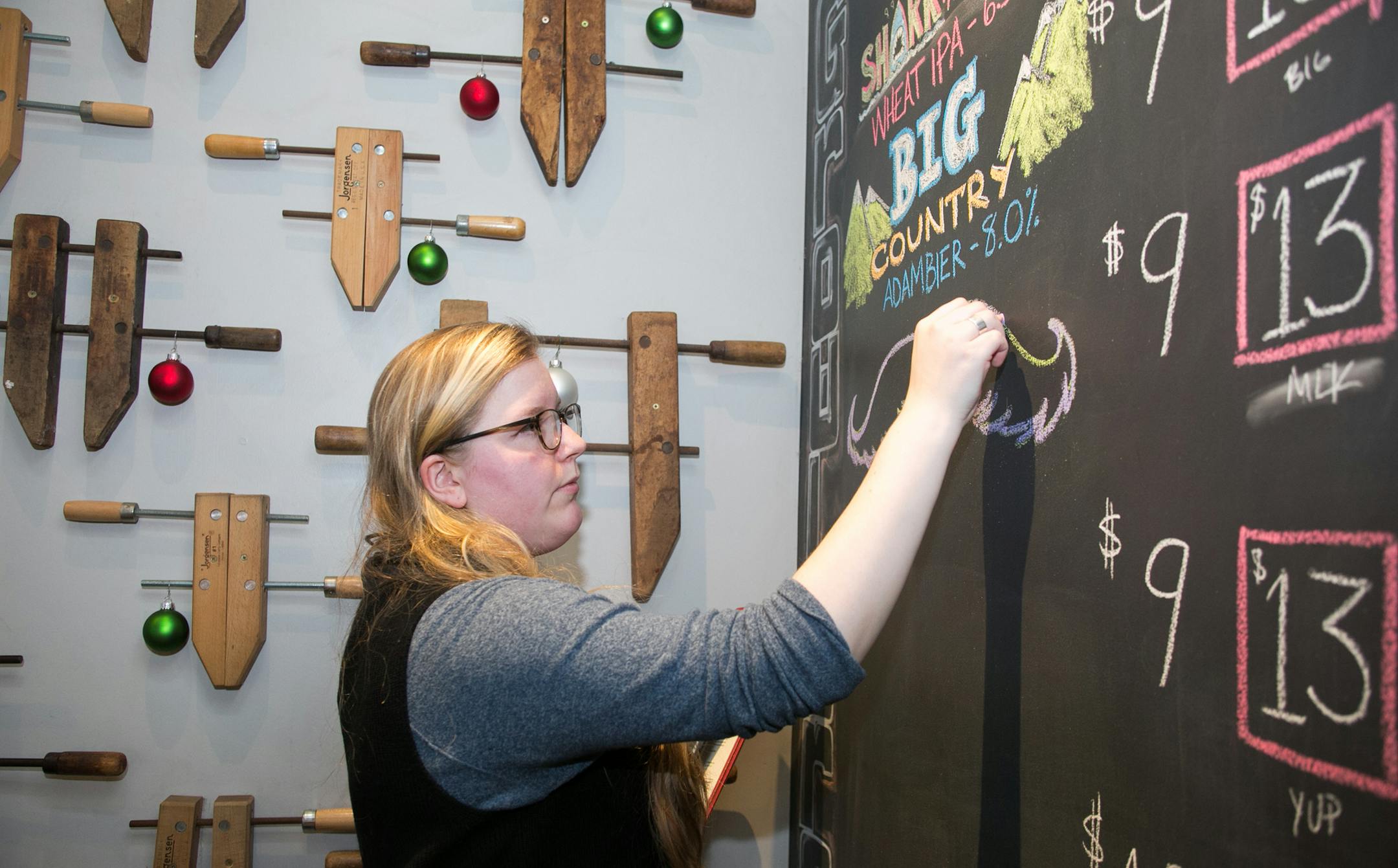 Gabby Golub updates the Dry DryHop Brewers growler chalkboard on Dec. 16, 2016, at the brewpub in Chicago's Lakeview East neighborhood. Golub does chalkboard art for different bars and restaurants in addition to driving for Lyft and working part time at her old high school.