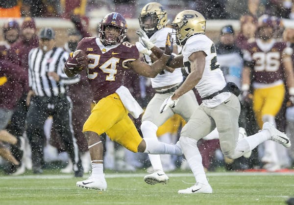 Gophers running back Mohamed Ibrahim ran with the ball despite pressure from Purdue safety Navon Mosley during the third quarter Saturday at TCF Bank 