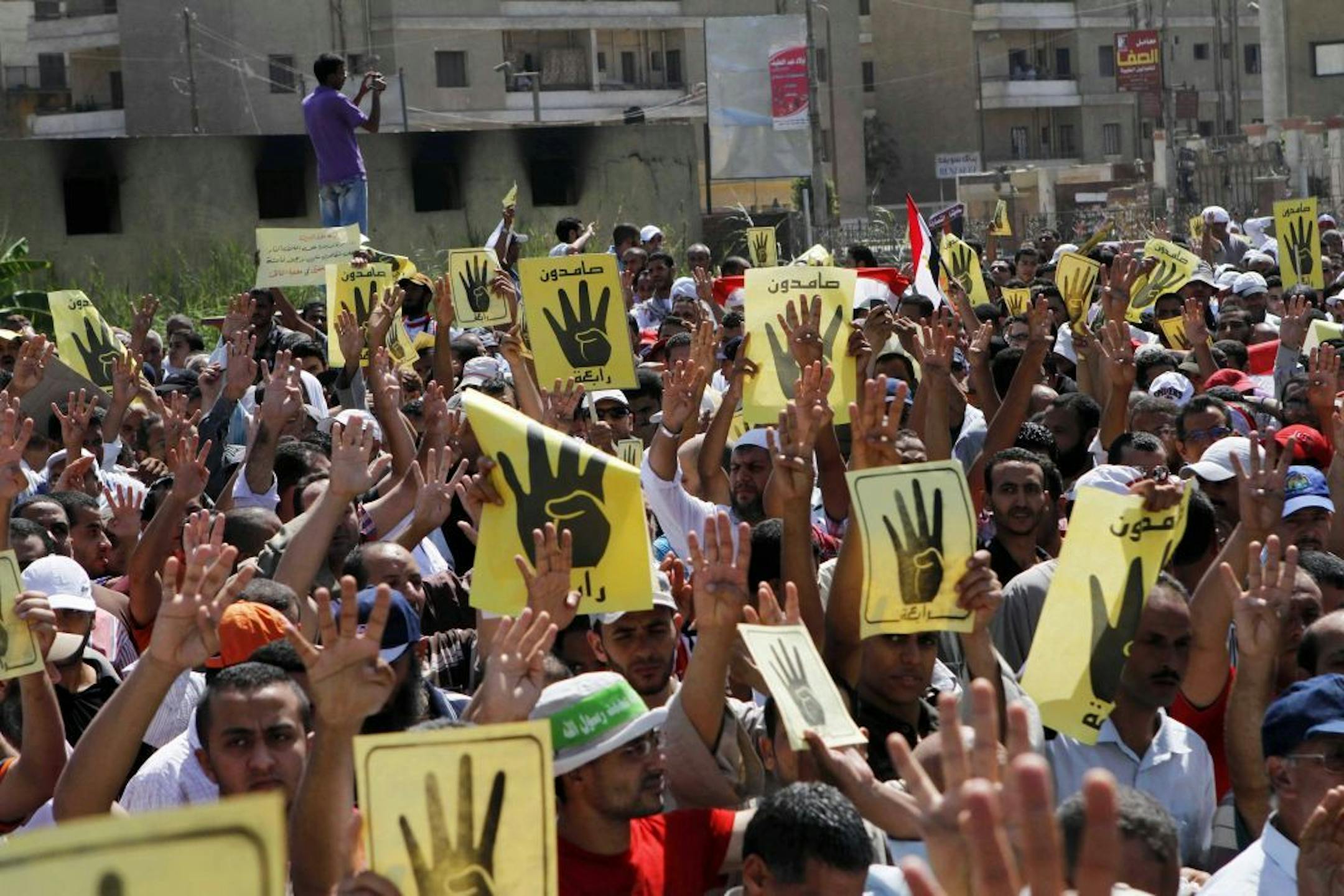 People raise their hands and banners to show a hand gesture of an open palm with four raised fingers during a protest in Beni Sueif, south of Cairo, Egypt, Friday, Aug. 30, 2013. The gesture became a symbol for the main sit-in of supporters of Egypt's ousted President Mohammed Morsi near the Rabaah al-Adawiya mosque in Cairo. The sit-in was violently disbanded.