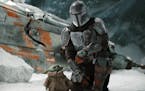 This image released by Disney Plus shows Pedro Pascal, as Din Djarin, right, with The Child, in a scene from "The Mandalorian," premiering its second 