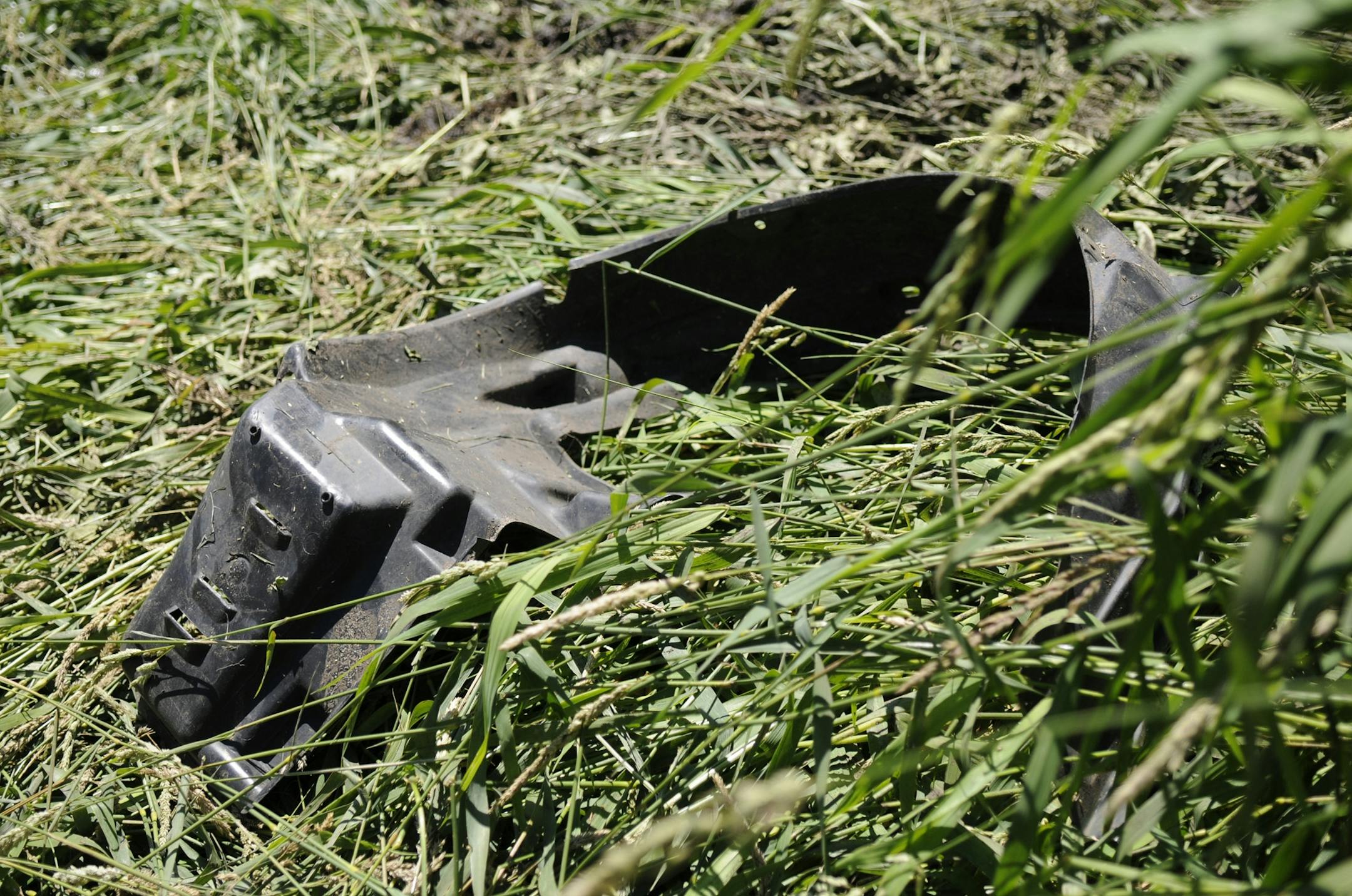 A plastic piece from a car is Monday, July 4, 2011 on a trampled path to the river where a man and two children died and two others were injured after their car overturned in the Sauk River off Stearns County Road 75 in Waite Park, Minn.