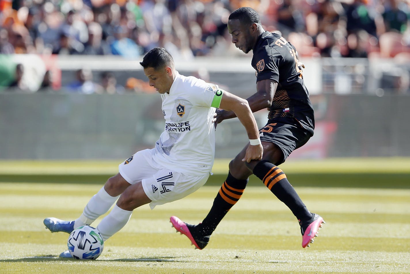 Los Angeles Galaxy forward Javier "Chicharito" Hernandez (14) moves the ball around Houston Dynamo defender Maynor Figueroa, right, during the first half of an MLS soccer match Saturday in Houston.