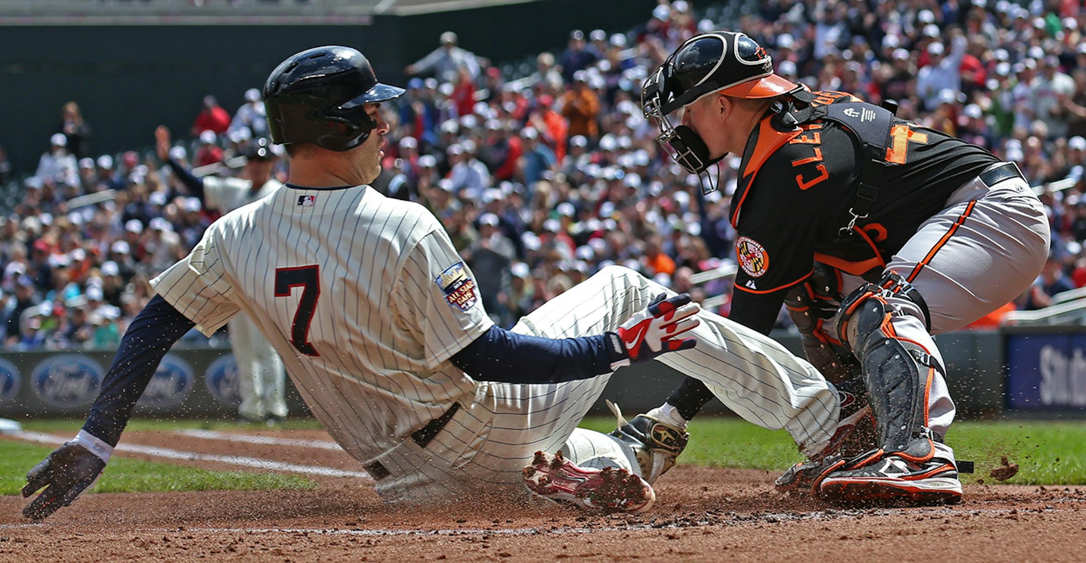 Joe Mauer was safe at home to score as Baltimore's Steve Clevenger caught the ball in first inning action, at Target Field on 5/3/14.
