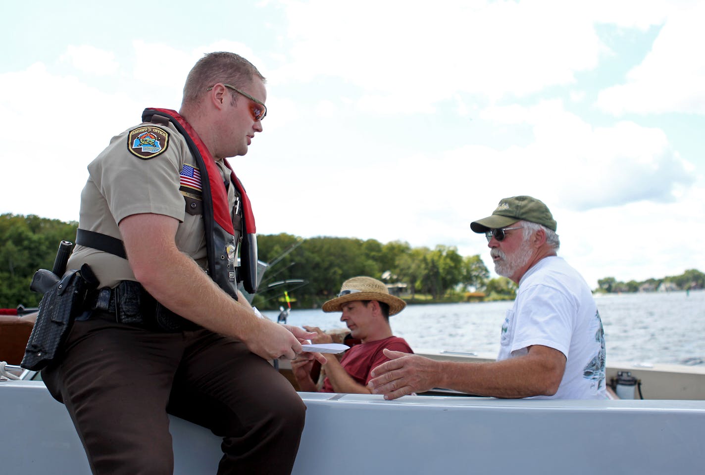 Adam Hernke, water patrol sheriff&#x2019;s deputy, stops Roberts Krebs, center, of Maple Grove, and George Mackereth, right, of Minneapolis, and gives them a ticket for not having a pfd type 4 throwable on Lake Minnetonka on Saturday, August 3, 2013. ] (ANNA REED/STAR TRIBUNE) anna.reed@startribune.com (cq)