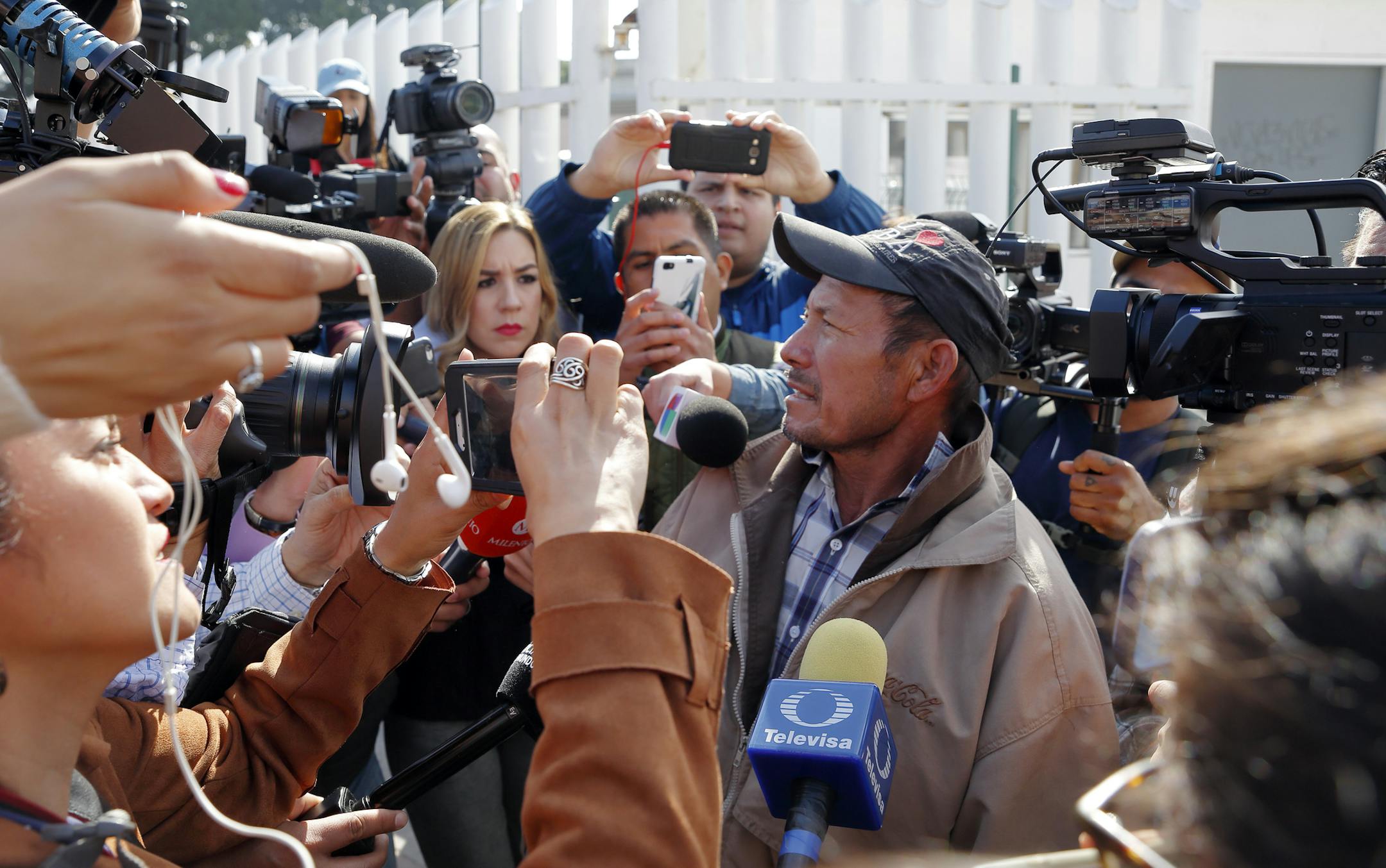 Carlos Catarldo Gomez, of Honduras, right, is surrounded by reporters after leaving the United States, the first person returned to Mexico to wait for his asylum trial date, in Tijuana, Mexico, Tuesday, Jan. 29, 2019. The Trump administration has launched an effort to make asylum seekers wait in Mexico while their cases wind through U.S. immigration courts despite mixed signals from Mexico on key issues. (AP Photo/Gregory Bull)