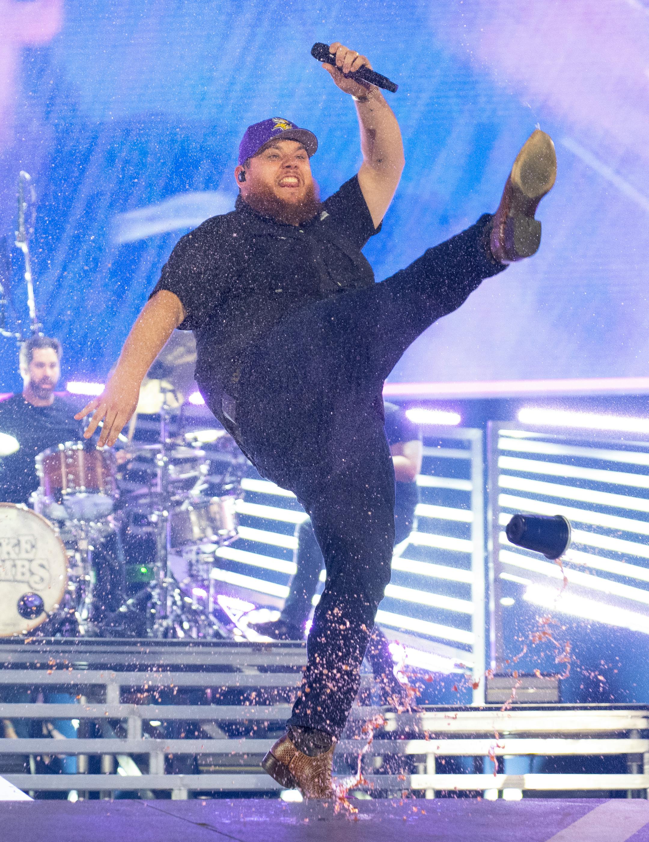 Luke Combs kicks his drink as he walks on stage to perform at U.S. Bank Stadium.