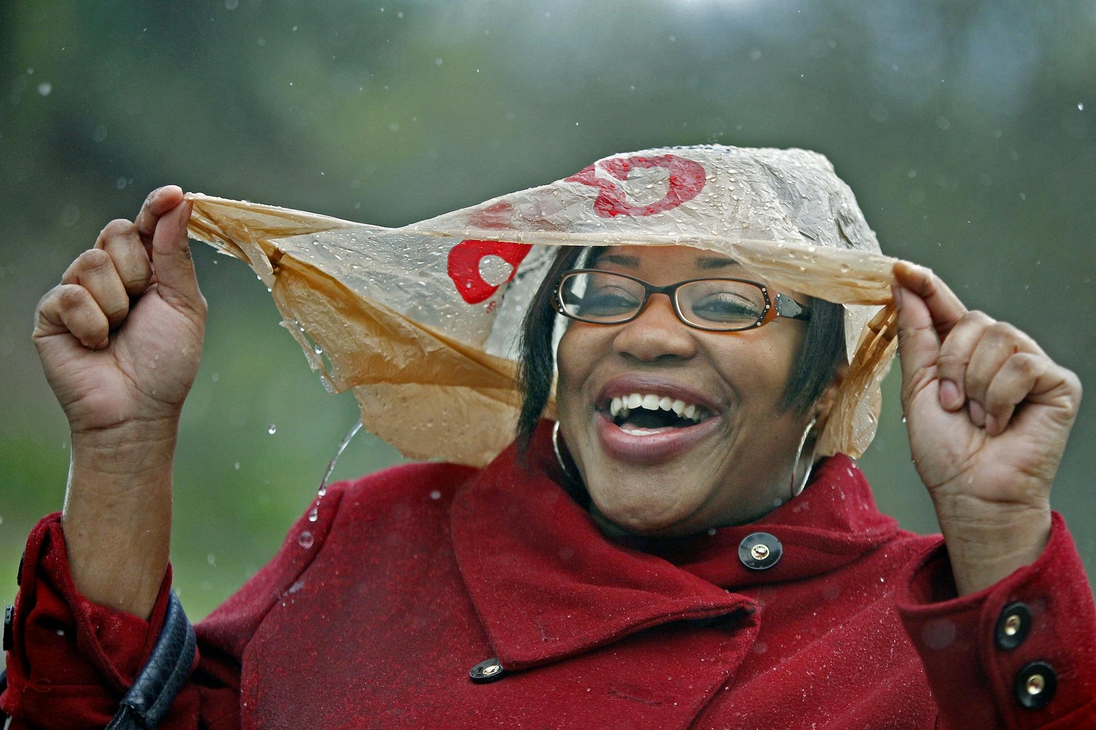 Elaine Evans got caught in the downpour with only a plastic bag for shelter as she waited for her bus near North 29th and Lyndale Avenues, Monday.