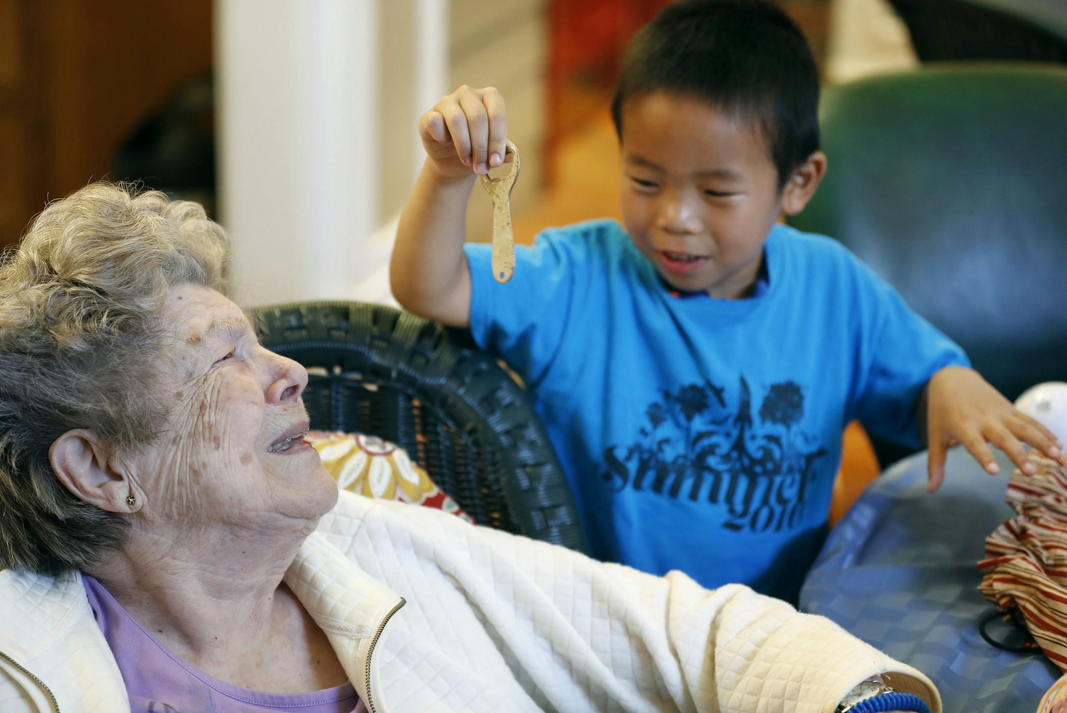 Ninety-five year old Irma a resident at Brookdale Senior Living reacts to Christopher Xu 6, after he showed her a bottle opener during a visit Wednesday August 17, 2016 in North Oaks, MN.] A new partnership between Kindercare and Brookdale Senior Living is bringing elementary kids on monthly visits to see seniors with Alzheimer's Jerry Holt / jerry.Holt@Startribune.com