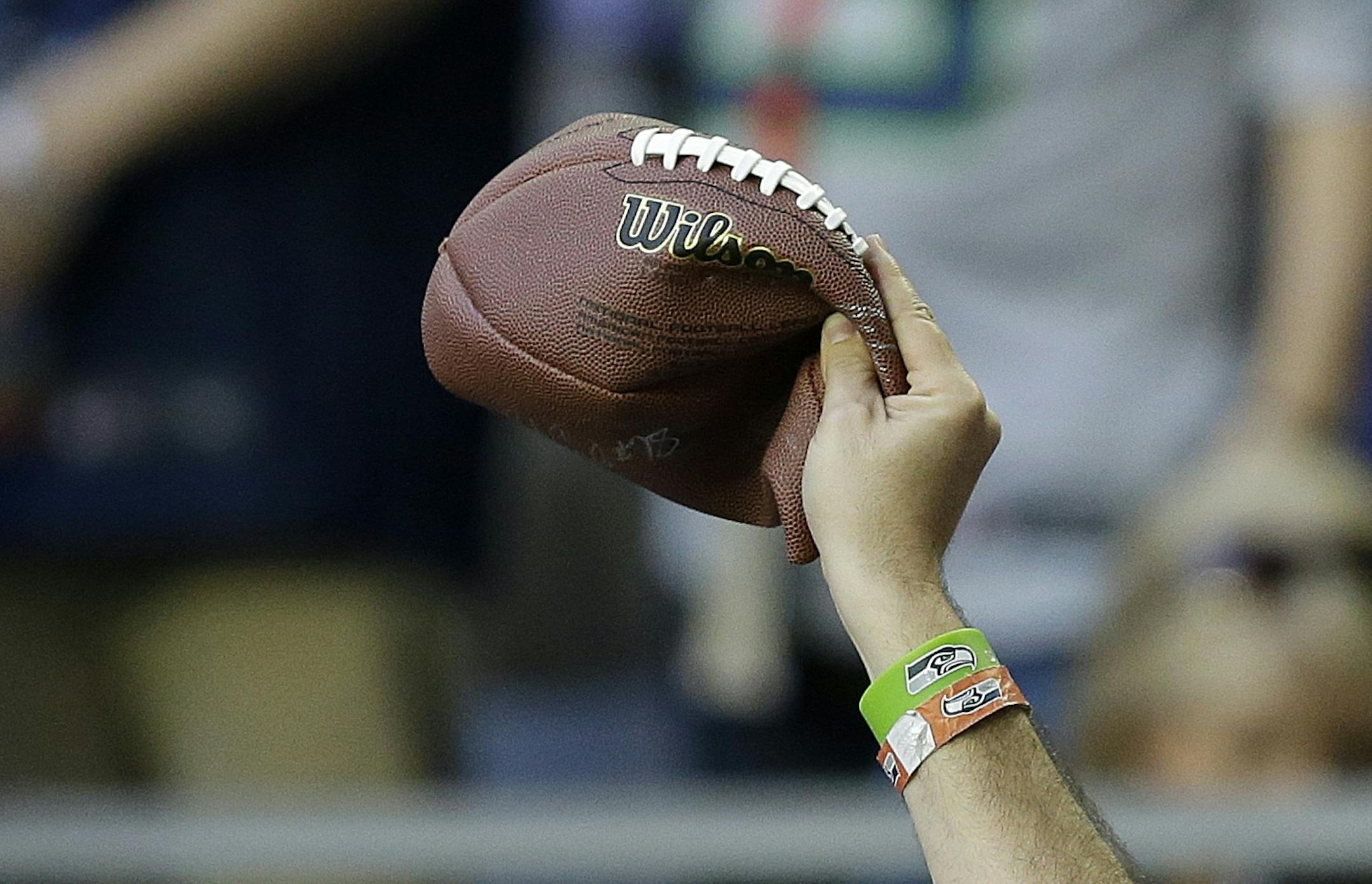 A Seattle Seahawks fan holds up a deflated football before the NFL Super Bowl XLIX football game between the Seahawks and the New England Patriots on Sunday, Feb. 1, 2015, in Glendale, Ariz. (AP Photo/Brynn Anderson) ORG XMIT: NFL1