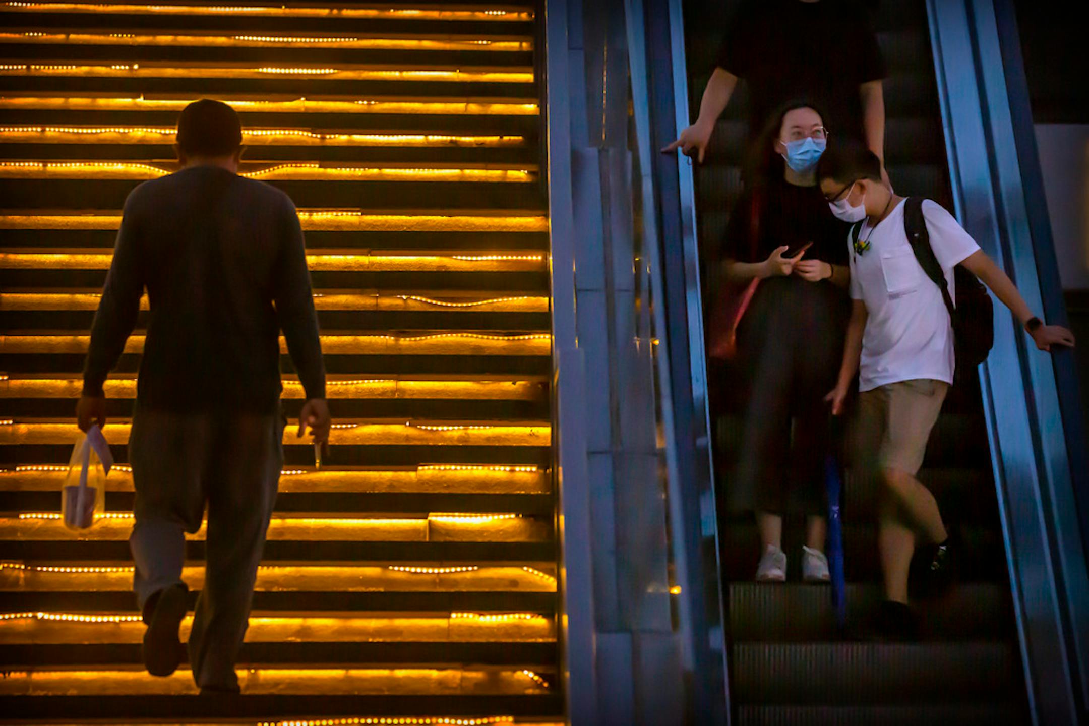 People wearing face masks to protect against the coronavirus rode an escalator at a shopping and office complex in Beijing.
