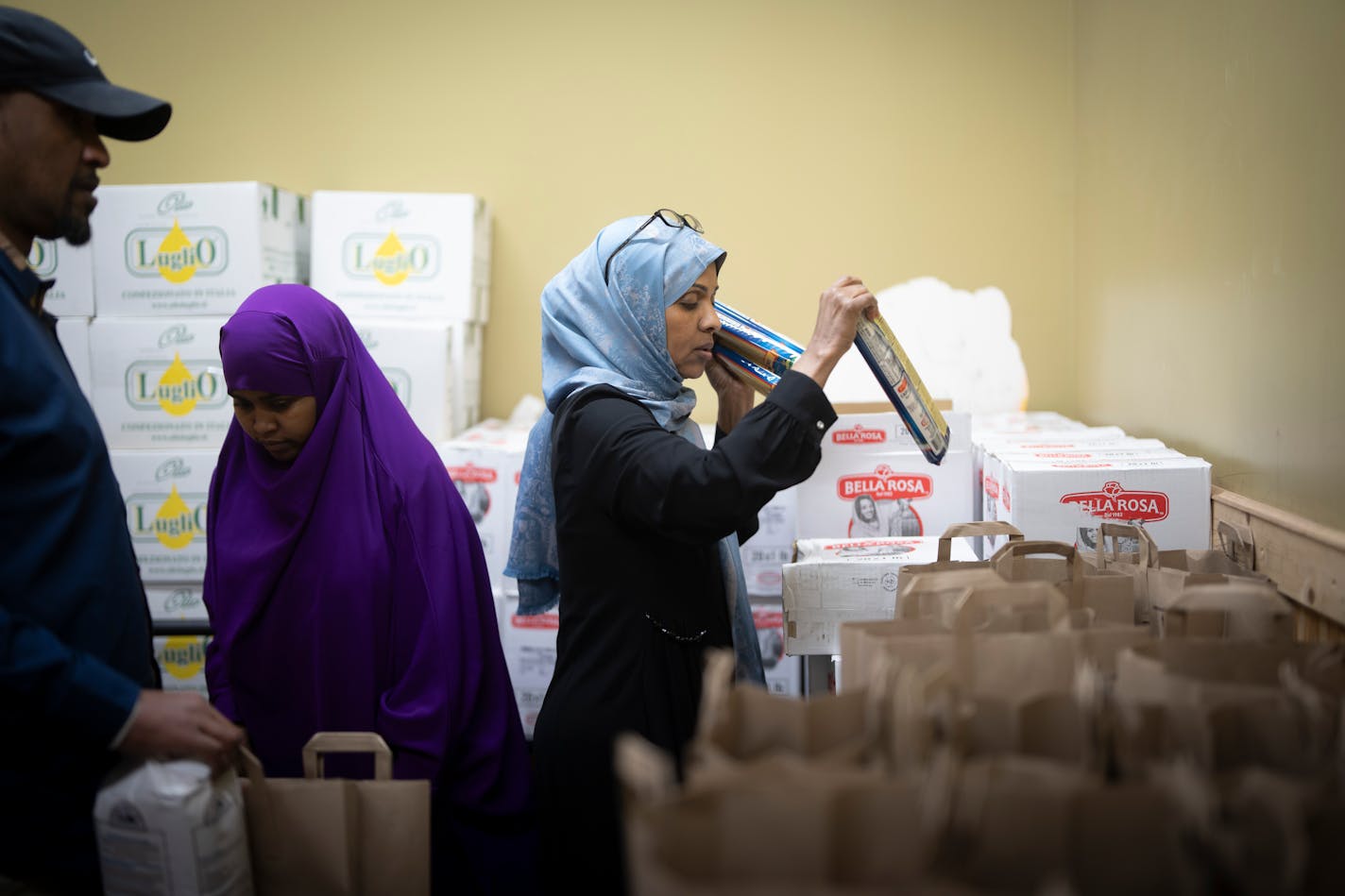 Fartun Weli packs up bags of food for donations at Halal Food Shelf on Wednesday, Dec. 13, 2023 in Minneapolis, Minn. Also pictured is Leyla Ahmed in purple and Mohamud Abdi also packing bags. ] RENEE JONES SCHNEIDER • renee.jones@startribune.com