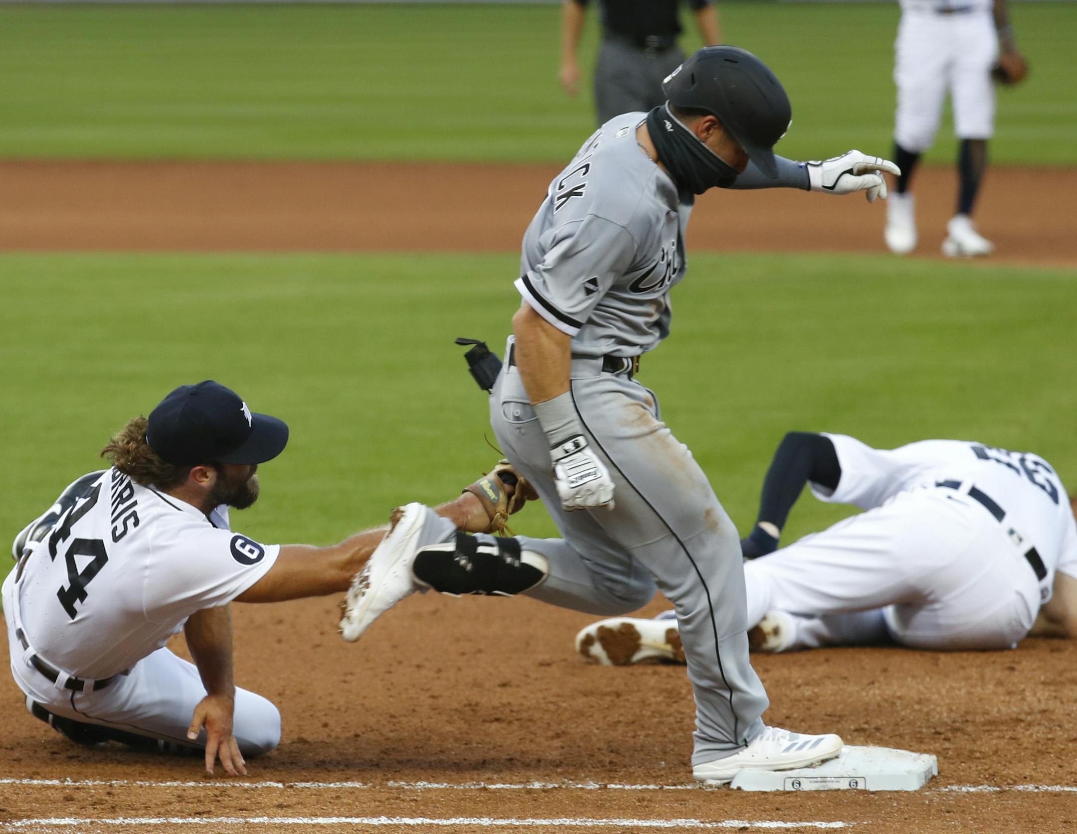 Detroit Tigers pitcher Daniel Norris, left, dives to tag out Chicago White Sox's Danny Mendick, center, as first baseman C.J. Cron (26) lies injured on the field in the fourth inning of a baseball game in Detroit, Monday, Aug. 10, 2020. (AP Photo/Paul Sancya)