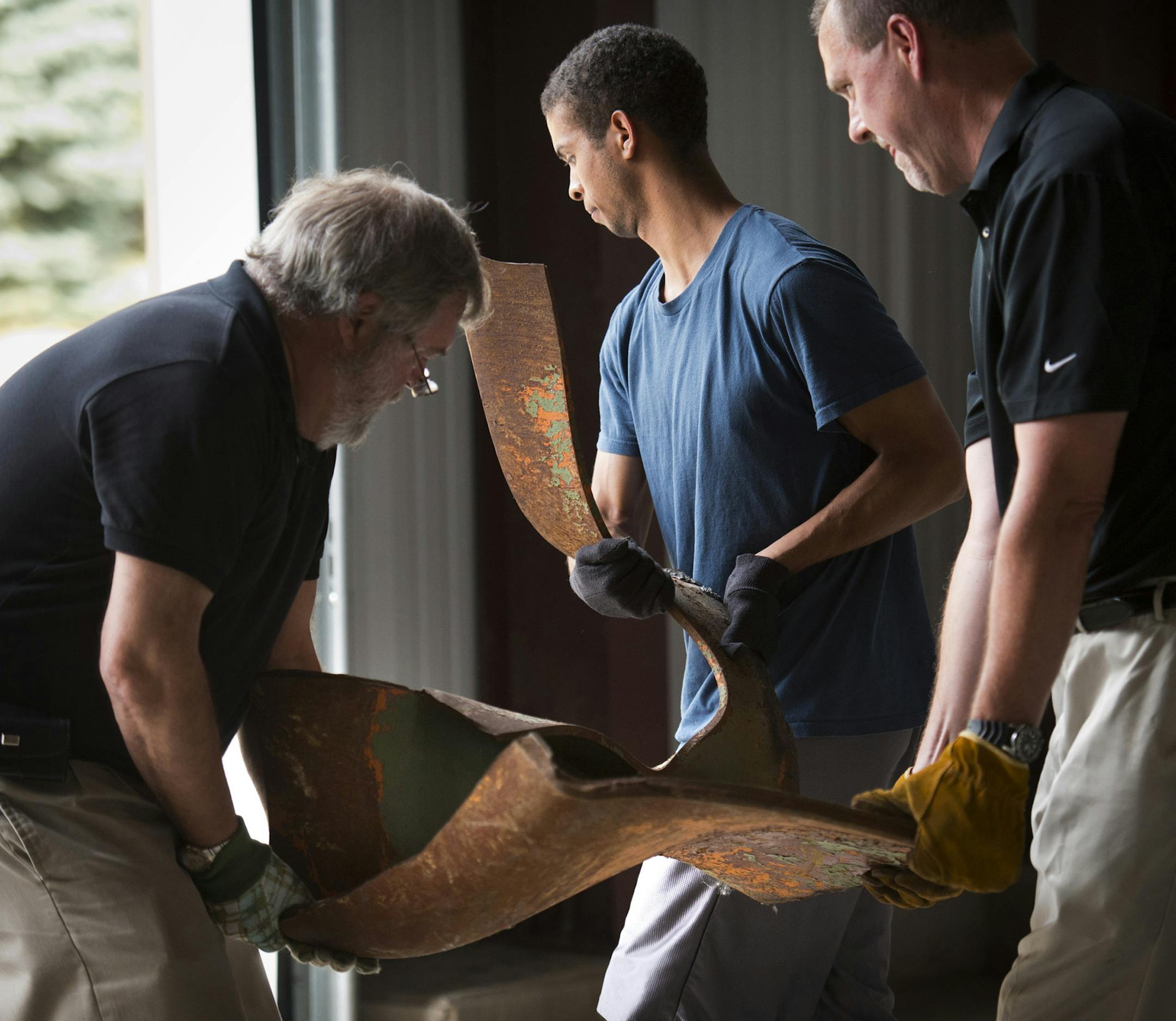 Attorney Bill Harper, Andrew Hausmann, whose father was killed in the collapse and attorney Dan Boerigter carried out a large piece of 35W Bridge remnant. The Minnesota Department of Transportation began distributing remnants of the I-35W bridge that collapsed in 2007 to eligible recipients Wednesday afternoon. The Minnesota State Legislature passed legislation in 2013 that specifies who is eligible for the steel. Wednesday, August 28, 2013 ] GLEN STUBBE * gstubbe@startribune.com ORG XMIT: MIN13