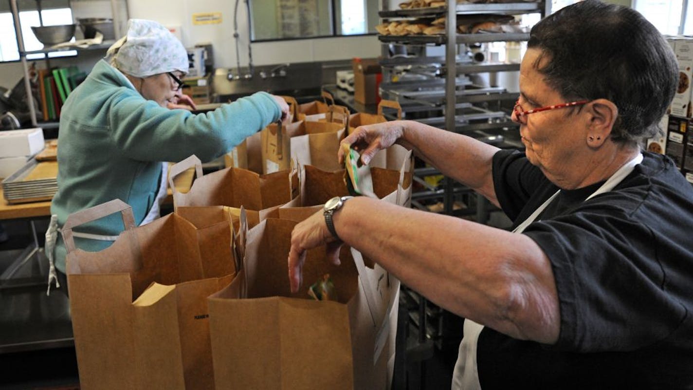 Open Arms of Minnesota volunteers Joan Hawkinson , left, and Donna Varns packed grocery bags on Monday for needy clients.