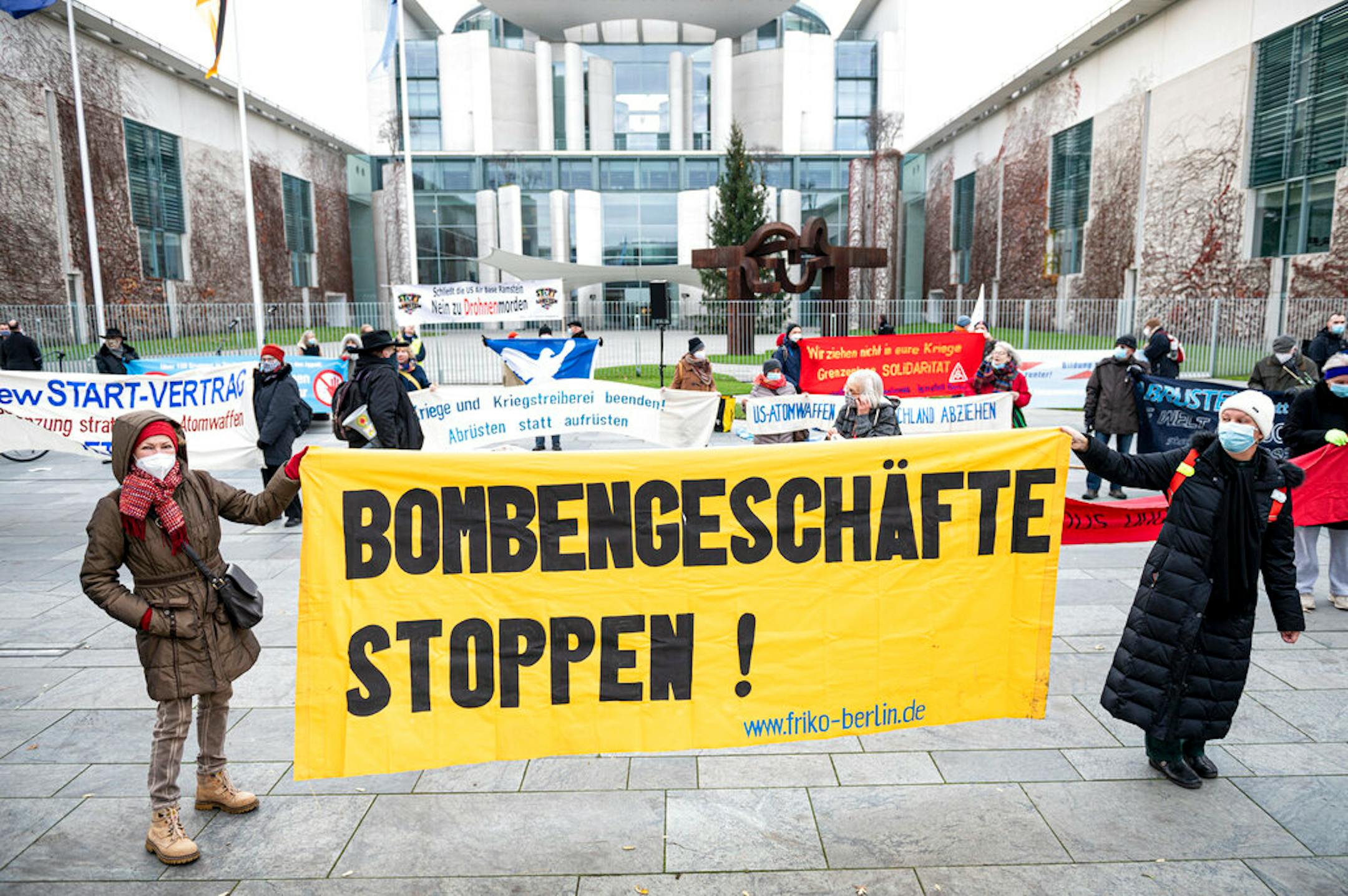 Participants of the action day "Disarm instead of rearming" stand in front of the Federal Chancellery with a banner saying "Stop bomb deals! in Berlin, Germany, Saturday, Dec. 5, 2020.