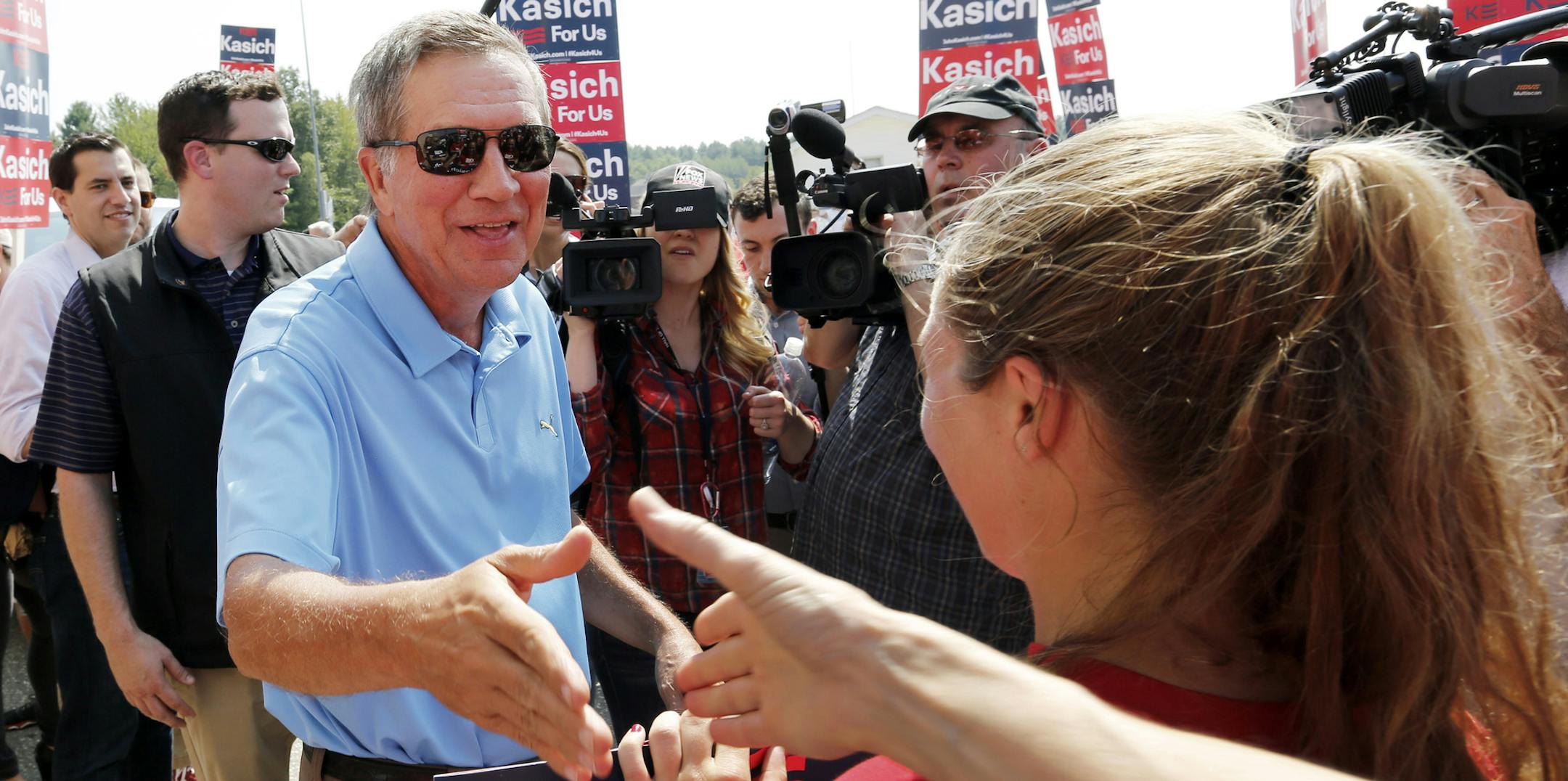 Republican presidential candidate Gov. John Kasich, R-Ohio, reachers out to shake hands with supporters before marching in the Labor Day parade Monday, Sept. 7, 2015, in Milford, N.H. (AP Photo/Jim Cole)