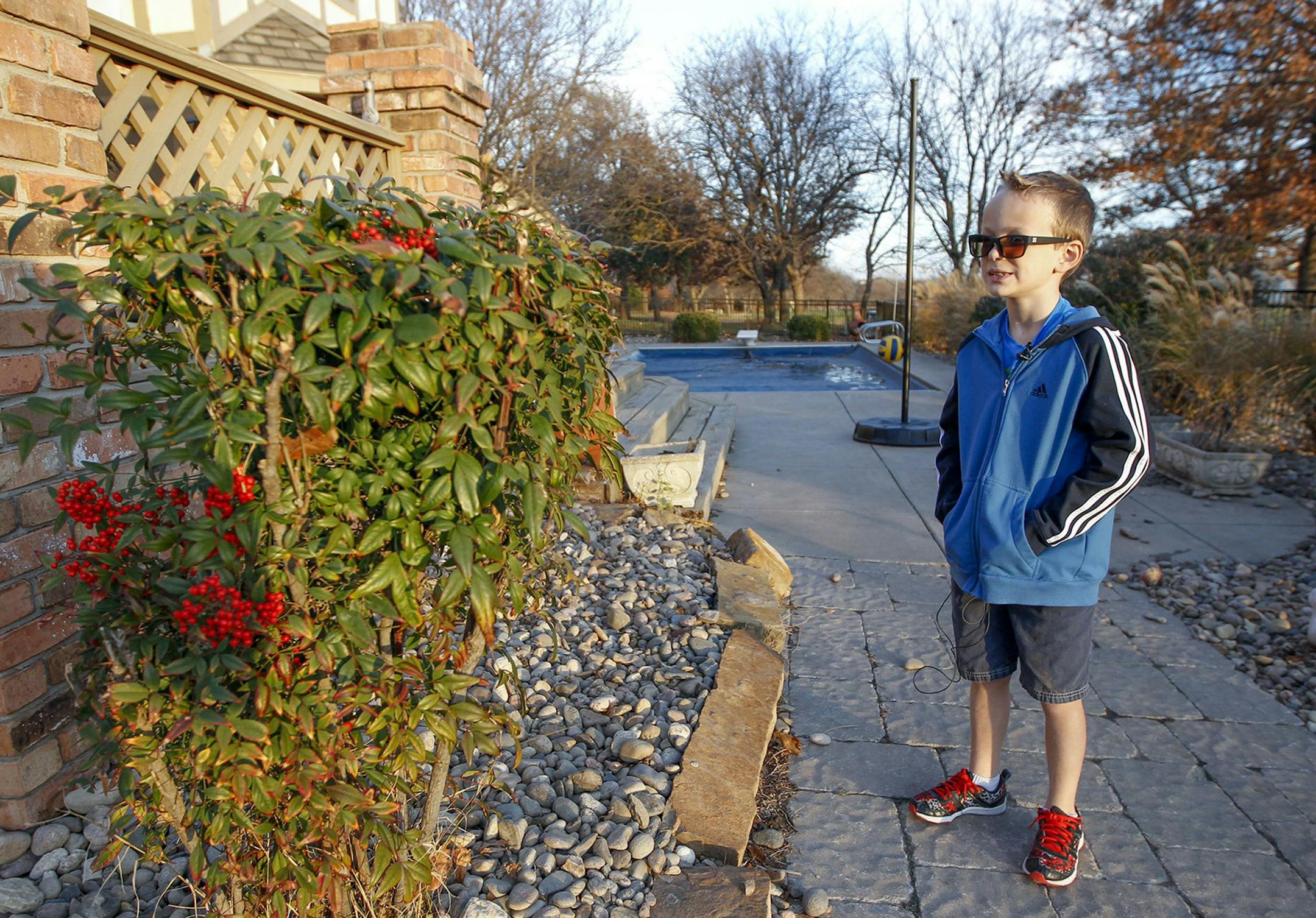 Seth Ogden notices the berries in a bush in his backyard for the first time after trying on his special Enchroma sunglasses which help him differentiate colors on Dec. 5, 2015 at his east Wichita, Kan., home. (Fernando Salazar/Wichita Eagle/TNS) ORG XMIT: 1177940