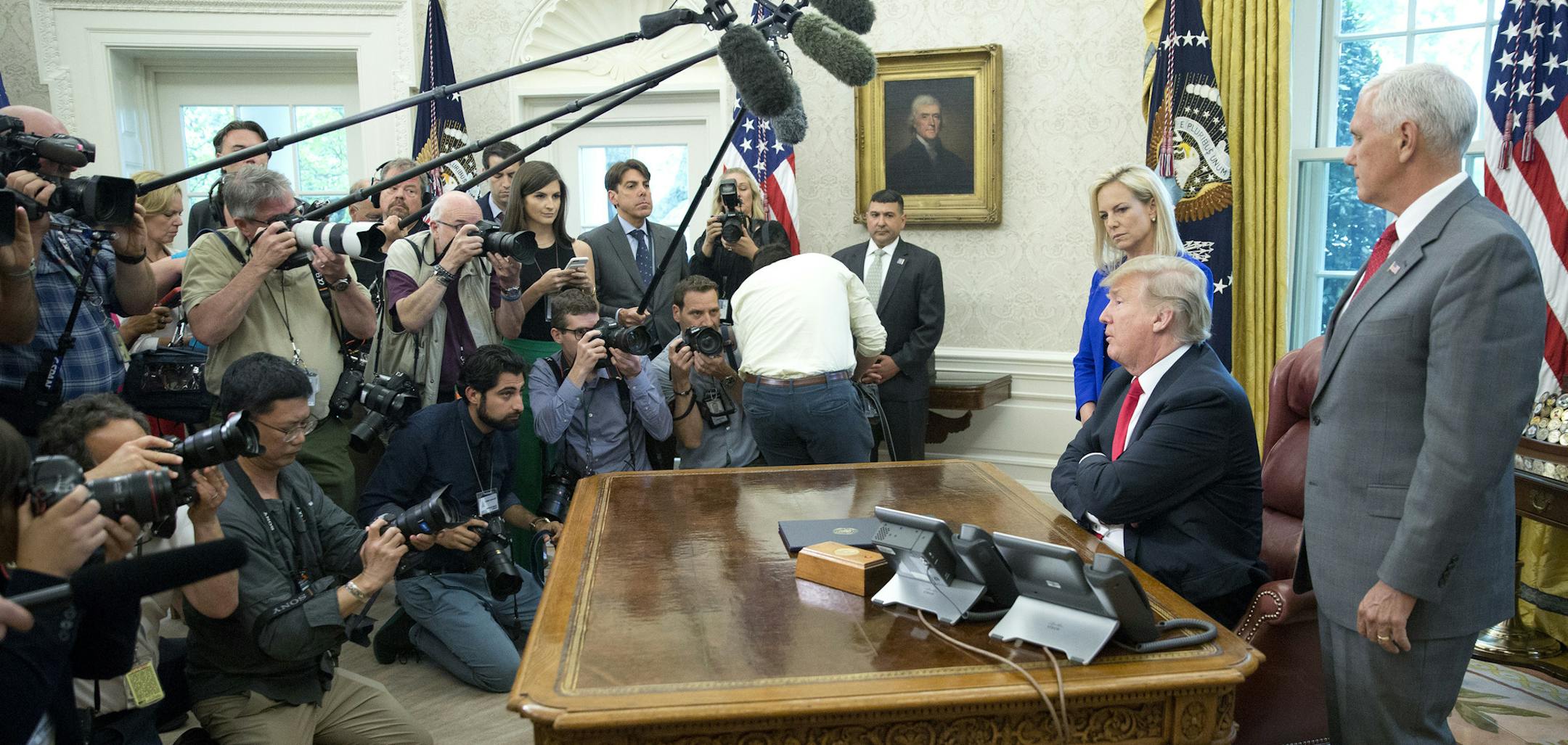 President Donald Trump speaks to members of the media after signing an executive order to end family separations at the border, during an event in the Oval Office of the White House in Washington, Wednesday, June 20, 2018. Standing with Trump are Homeland Security Secretary Kirstjen Nielsen and Vice President Mike Pence. (AP Photo/Pablo Martinez Monsivais)