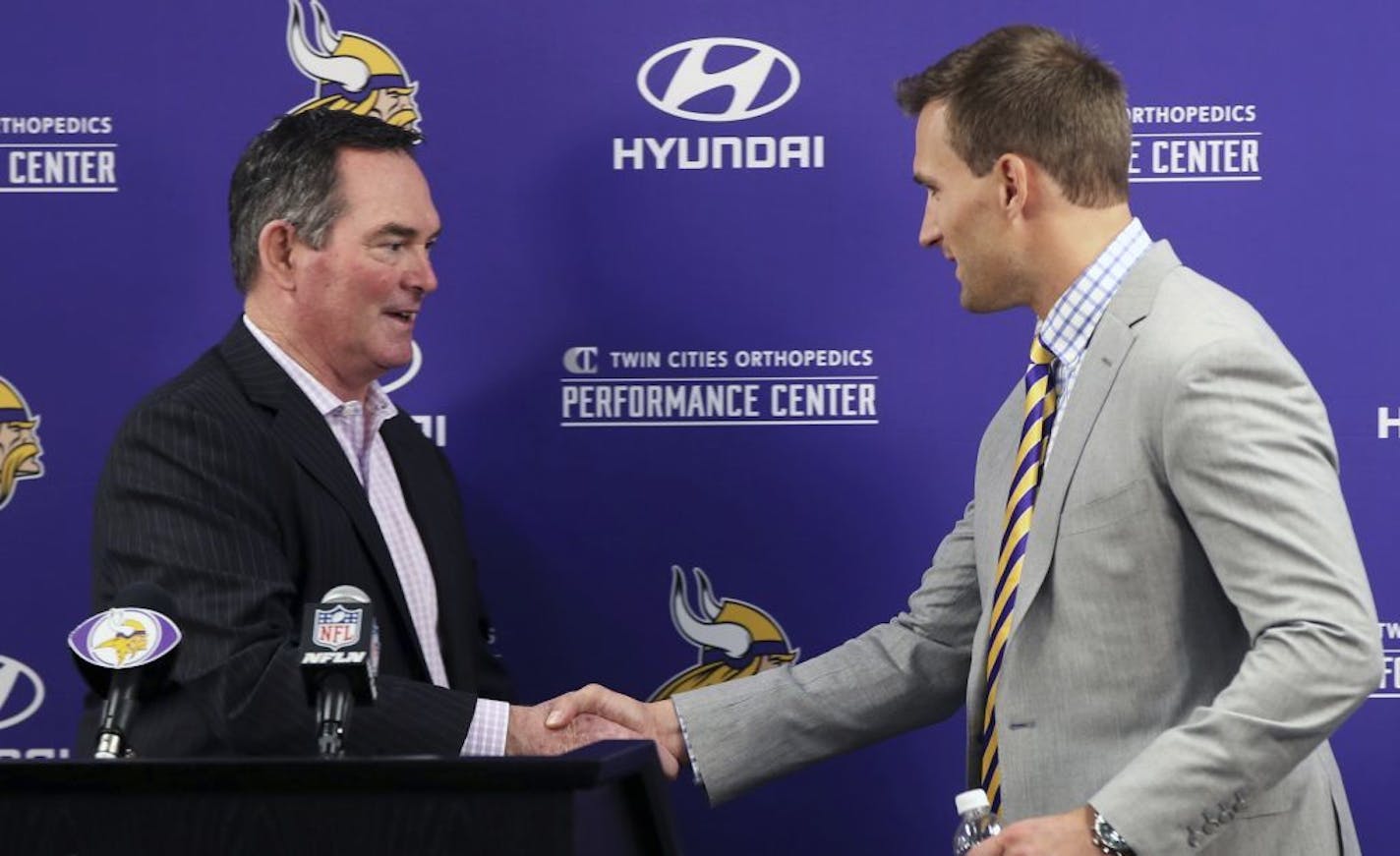 Minnesota Vikings new quarterback Kirk Cousins, right, is welcomed to the podium by head coach Mike Zimmer before addressing the media at a news conference after he was introduced after signing a three-year, $84 million contract at the NFL football team's new headquarters Thursday, March 15, 2018, in Eagan, Minn.