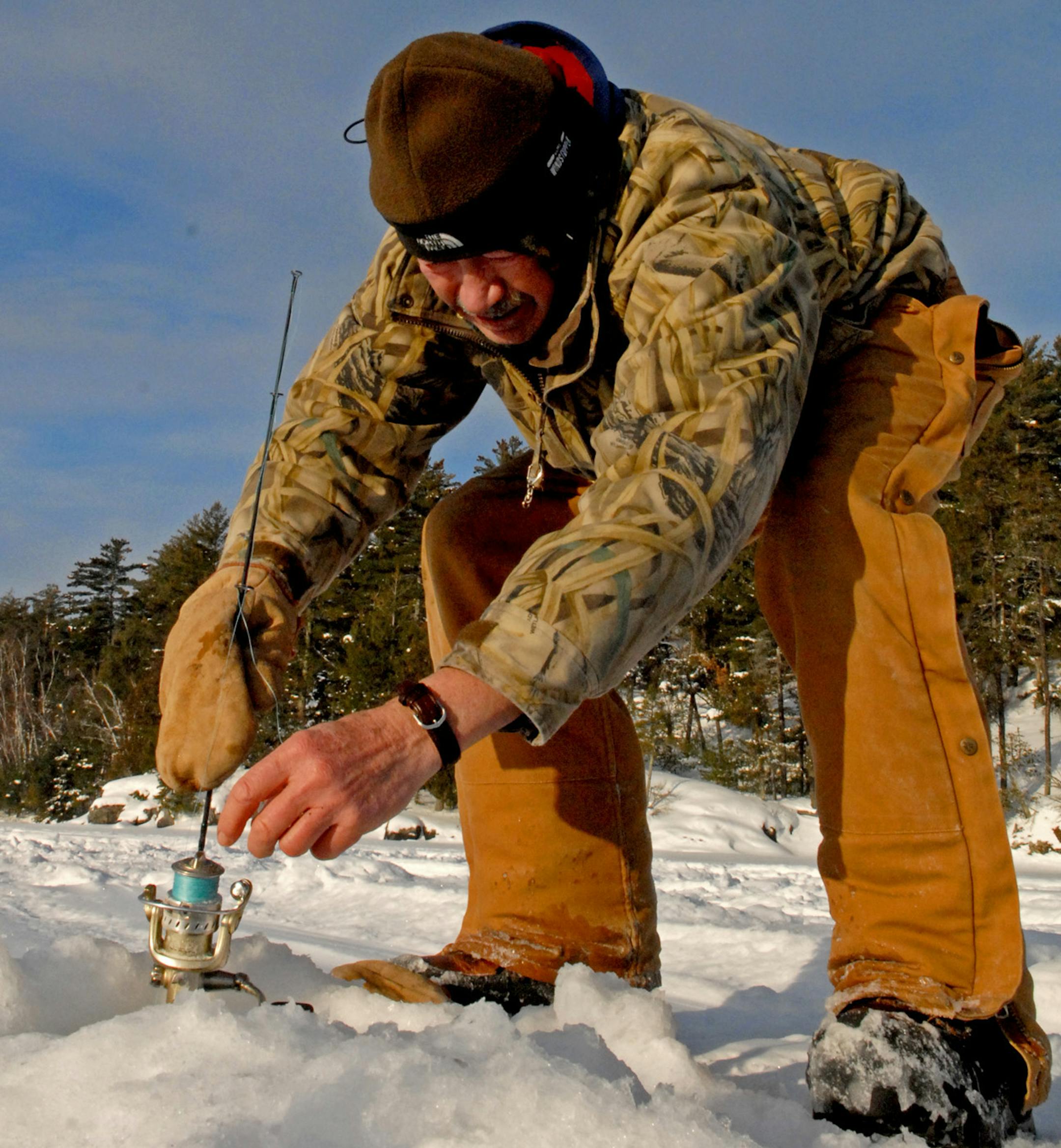 Keith Hanzel braces a rod in the snow while fishing for lake trout in Snowbank Lake.