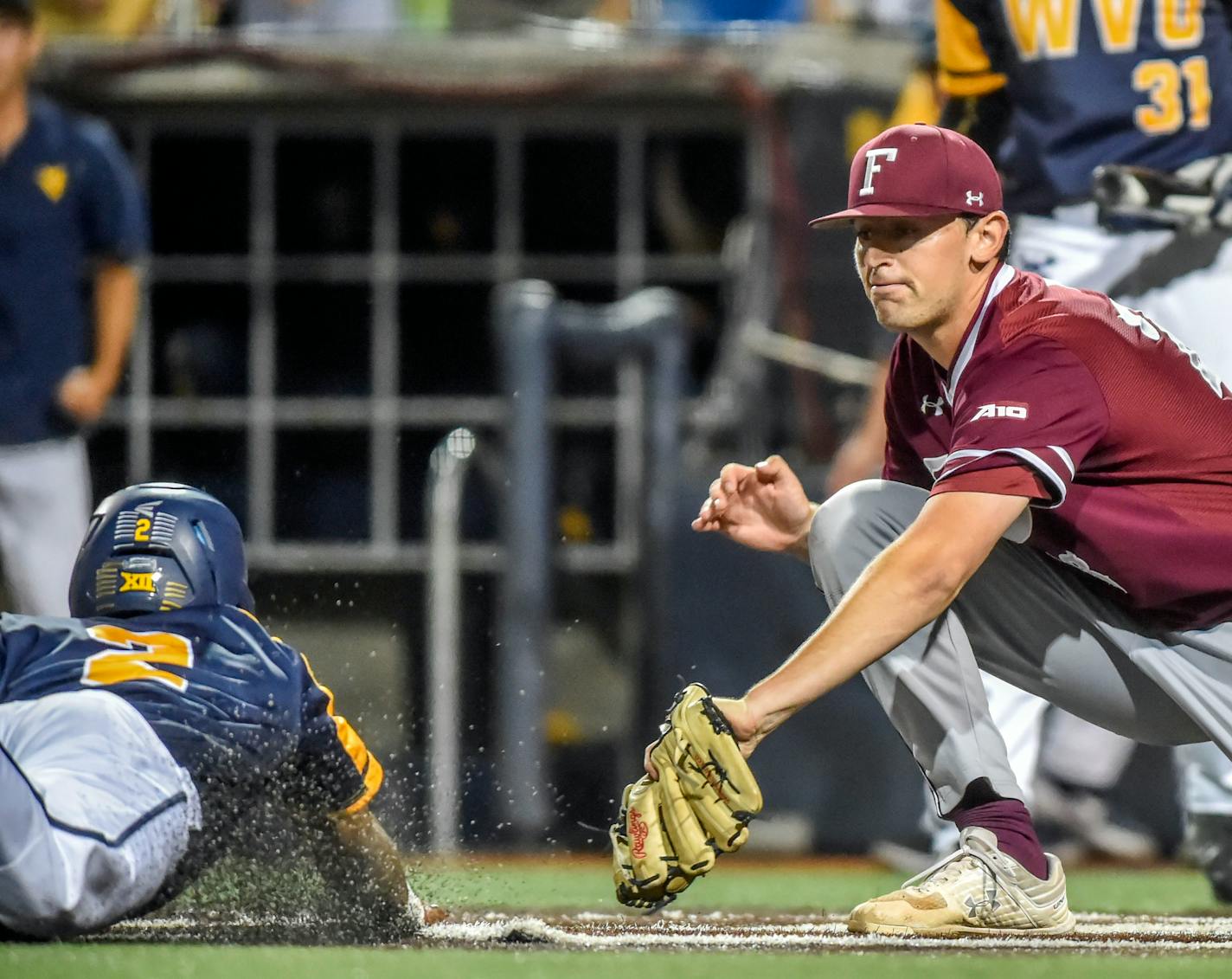 West Virginia's Tevin Tucker, left, beats a tag-attempt by Fordham's John Stankiewicz, right, during an NCAA college baseball regional tournament Friday, May 31, 2019, in Morgantown, W.V. (William Wotring/The Dominion-Post via AP) ORG XMIT: WVMOR903