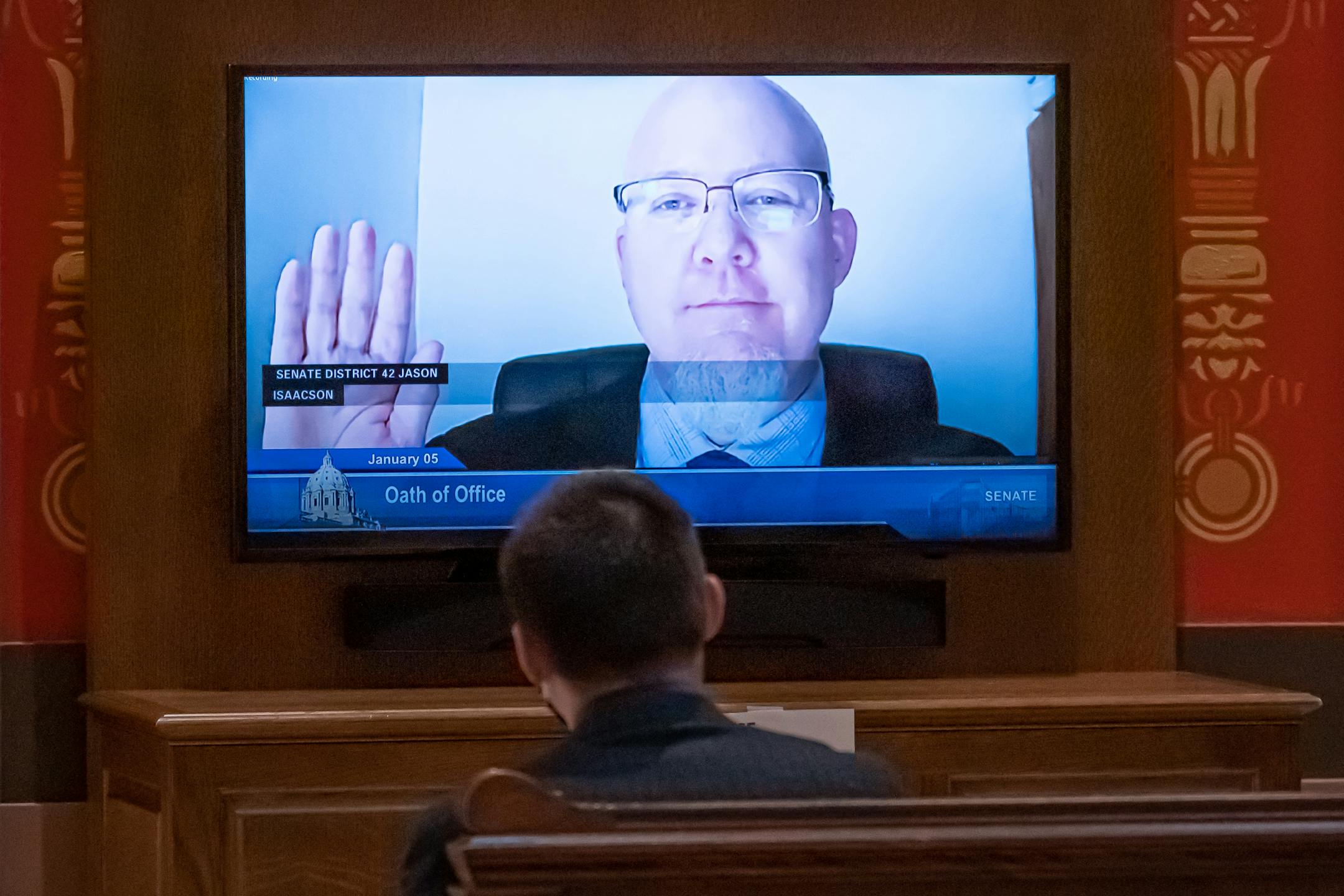 Sen. Jason Isaacson, DFL-Shoreview took the oath remotely, seen on monitors around the Capitol.  Most Senators were sworn in remotely at the Minnesota State Capitol. Later there was a leadership floor fight about continuing the term of President-ProTem of Sen. David Tomassoni, DFL-Chisholm.