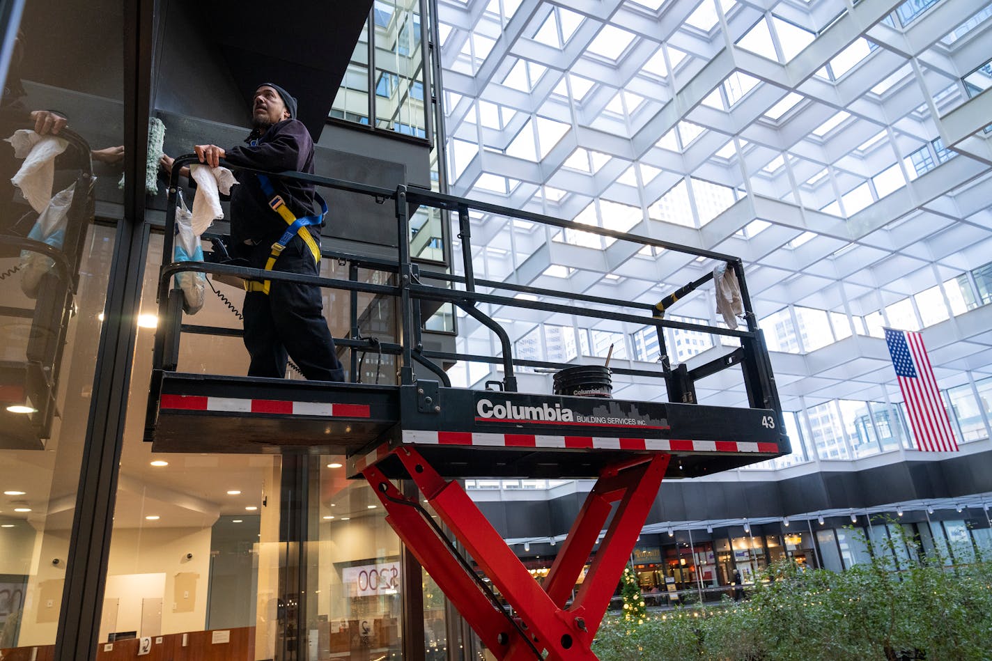 High-rise window cleaner Alex James from Columbia Building Services washes the interior windows of Crystal Court inside IDS Center in Minneapolis, Minn. Wednesday, Dec. 13, 2023. ] LEILA NAVIDI • leila.navidi@startribune.com