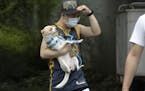 A man wearing a mask carries his dog along a street in Beijing on Thursday, June 25, 2020. In China, where the virus first appeared late last year, an