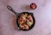 A savory skillet dish featuring chicken and vegetables on a pink background, complemented by the flavors of cherry jam and dijon mustard.
