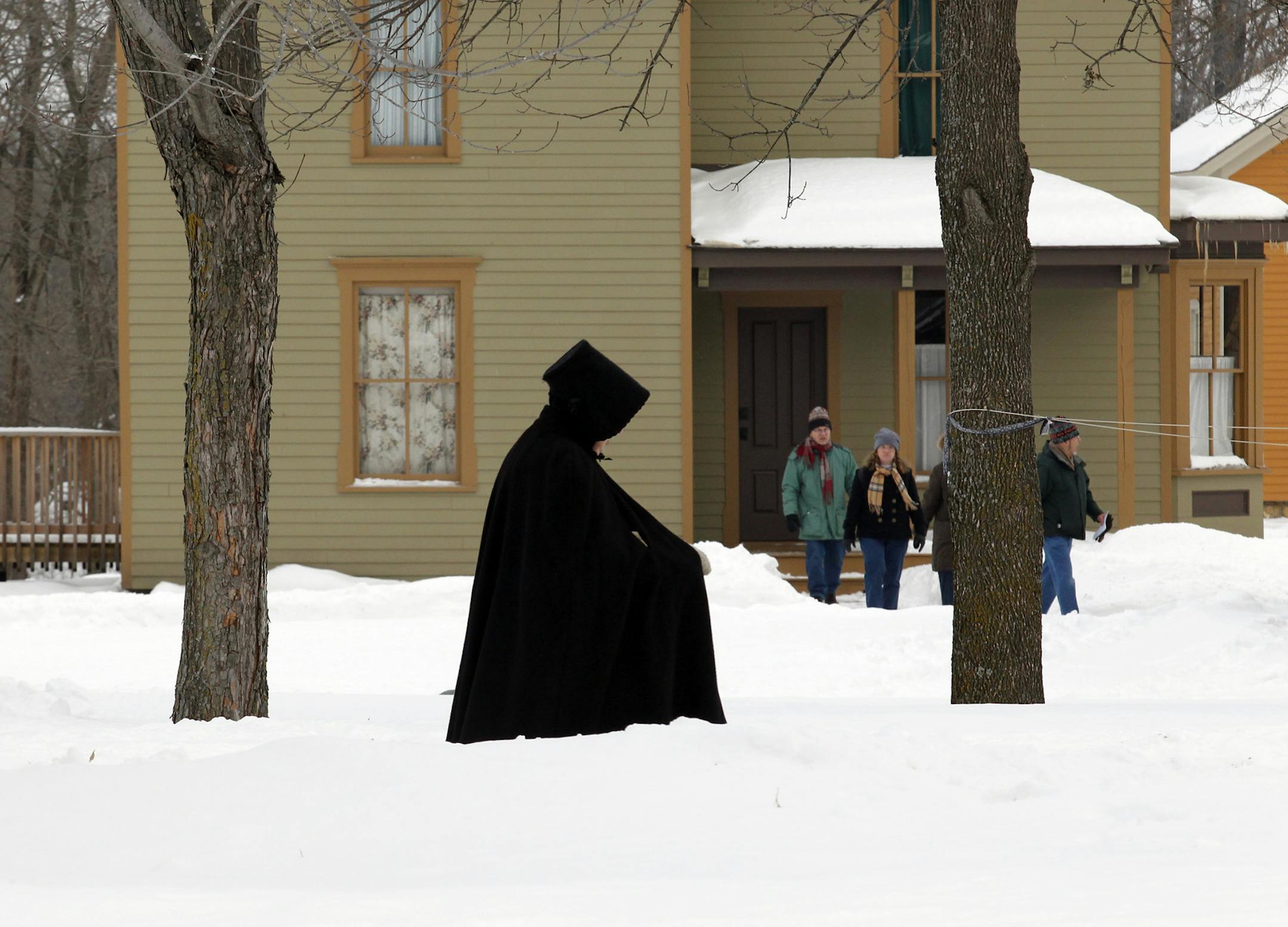 MARLIN LEVISON*mlevison@startribune.com GENERAL INFORMATION : ] Folkways of the Holidays - Holiday traditions of the 19th century were on display at The Landing in Shakopee. Trolley rides pulled by Percheron draft horses, constumed interpreters, crafts, folk art, music and dancing as well as an appearance by Santa were all part of the presentation. IN THIS PHOTO:A townswoman wearing traditional cold weather garb walked the street in front of a display house visted by the public.