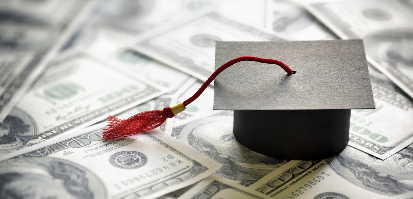 Graduation mortar board cap on one hundred dollar bills concept for the cost of a college and university education. istock photo