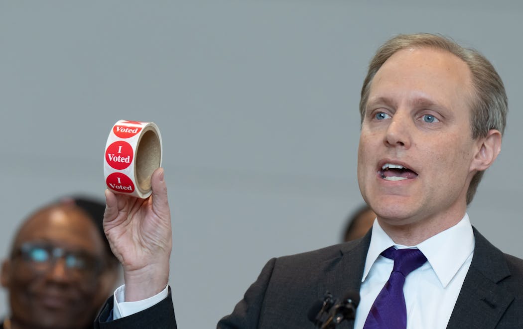 Secretary of State Steve Simon held up a roll of “I voted” stickers as he welcomed new voters. 