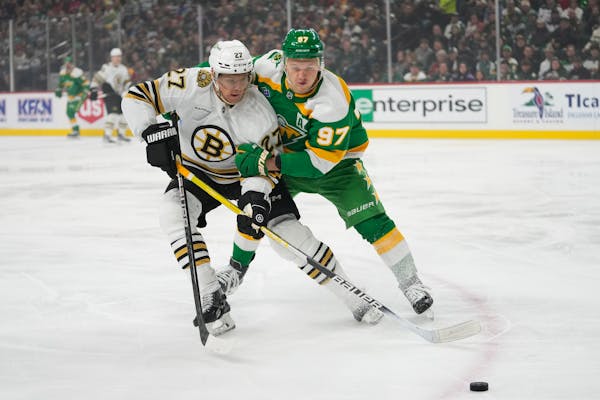 Bruins defenseman Hampus Lindholm (27) and Wild left wing Kirill Kaprizov (97) battled for the puck during the first period Saturday at Xcel Energy Ce